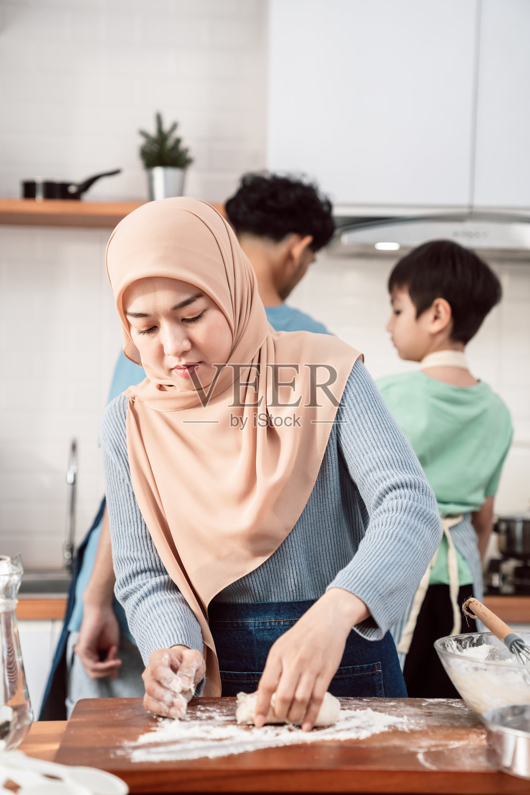 快乐的穆斯林家庭在准备自制甜点，父母教孩子们烘焙的艺术，分享微笑、爱与团聚的温馨节日家庭氛围照片摄影图片