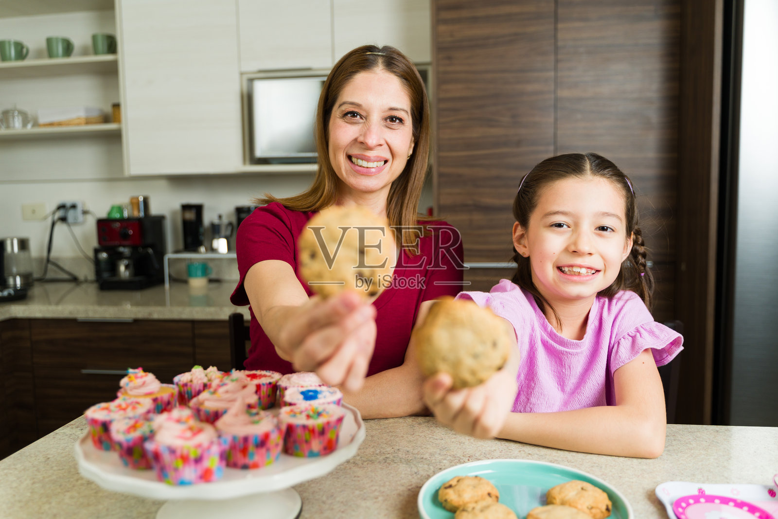 妈妈和小女孩在厨房展示新鲜出炉的饼干照片摄影图片