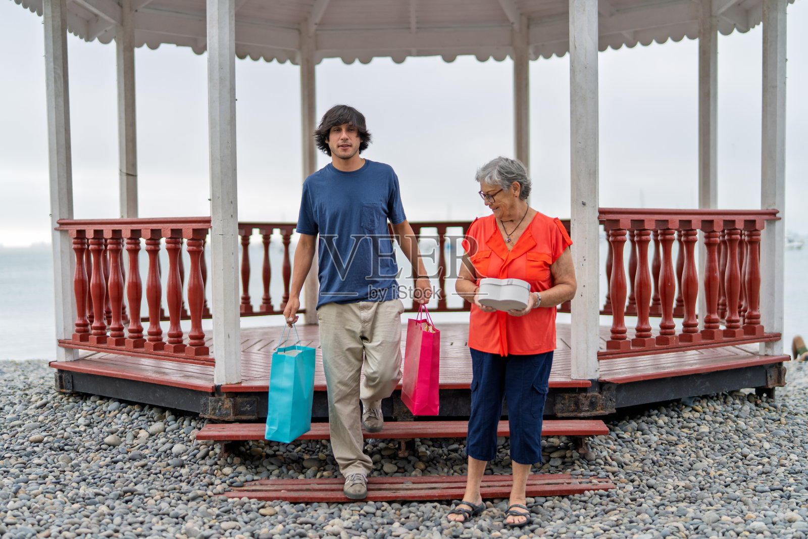 孙子提着购物袋与祖母一起走路照片摄影图片