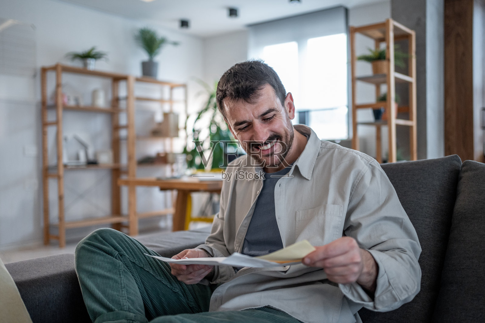 快乐的男人在家中阅读信件中的好消息照片摄影图片