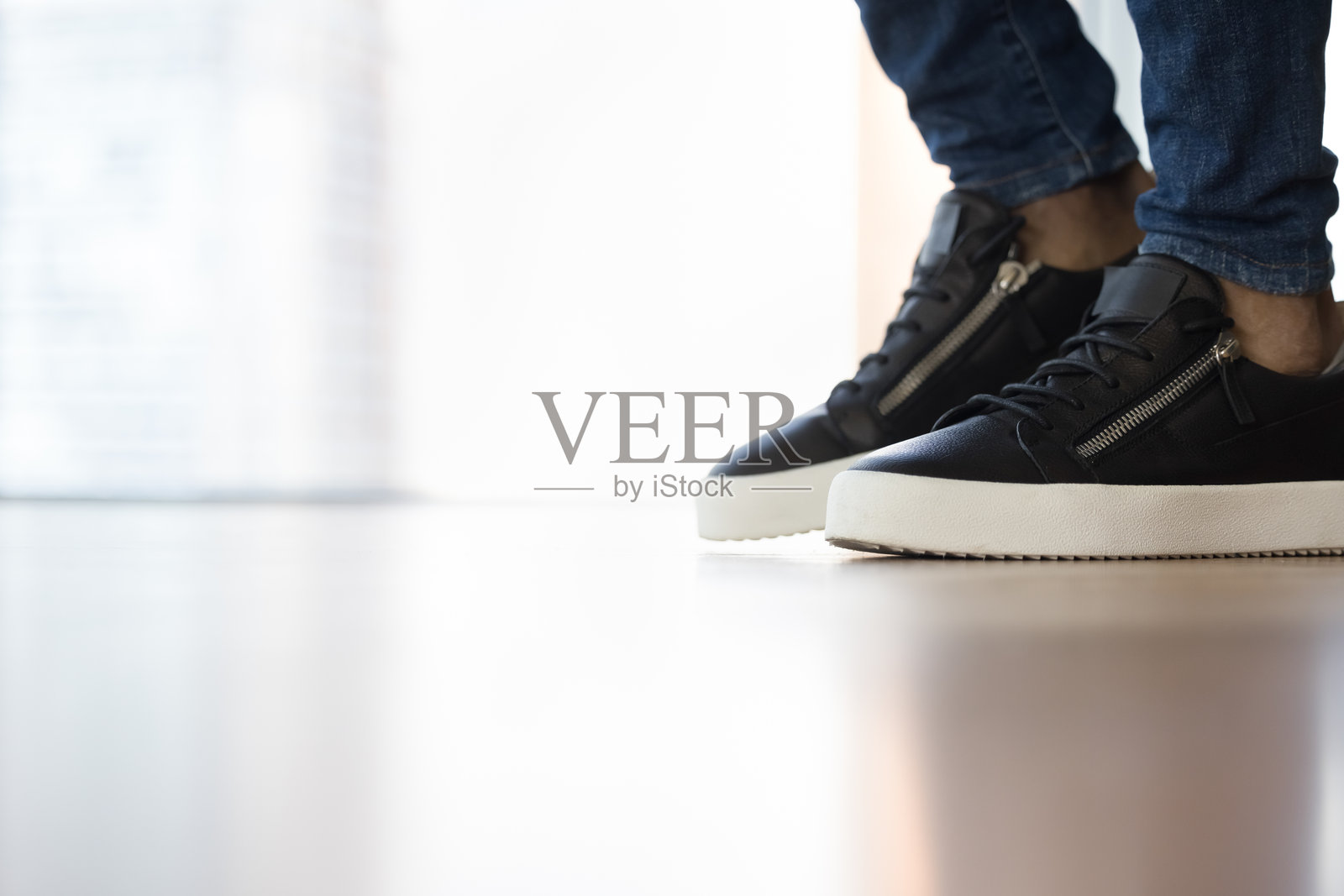 不明男子穿着运动鞋站在室内地板上，特写镜头照片摄影图片