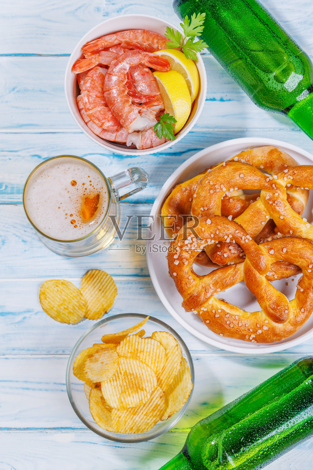 一张生动的照片，展示了一杯啤酒，周围是各种小吃和快餐。照片摄影图片