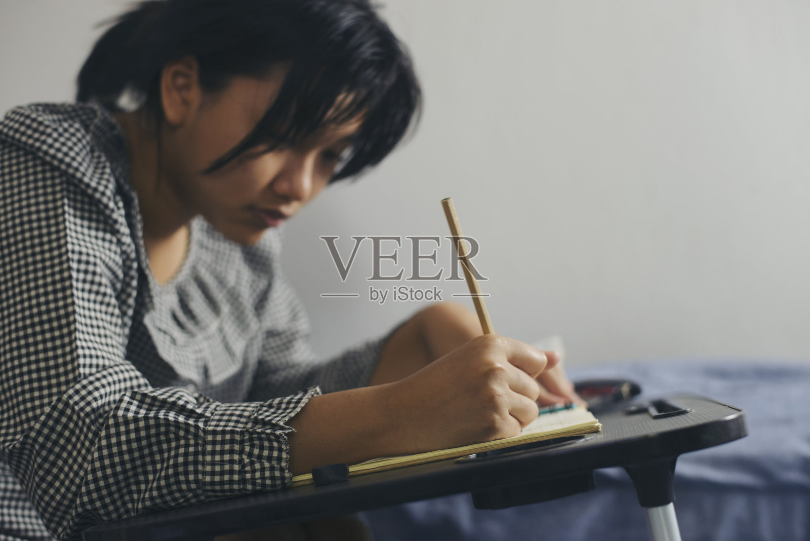 亚洲女孩在家里晚上做作业和阅读书籍。可爱的青少年在写作和做笔记，为考试做准备 - 教育概念。照片摄影图片