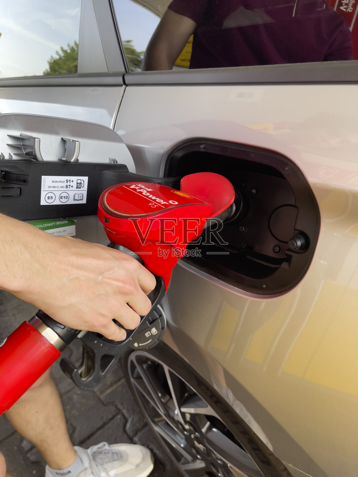 司机的手握着加油枪,为汽车的油箱加油。照片摄影图片