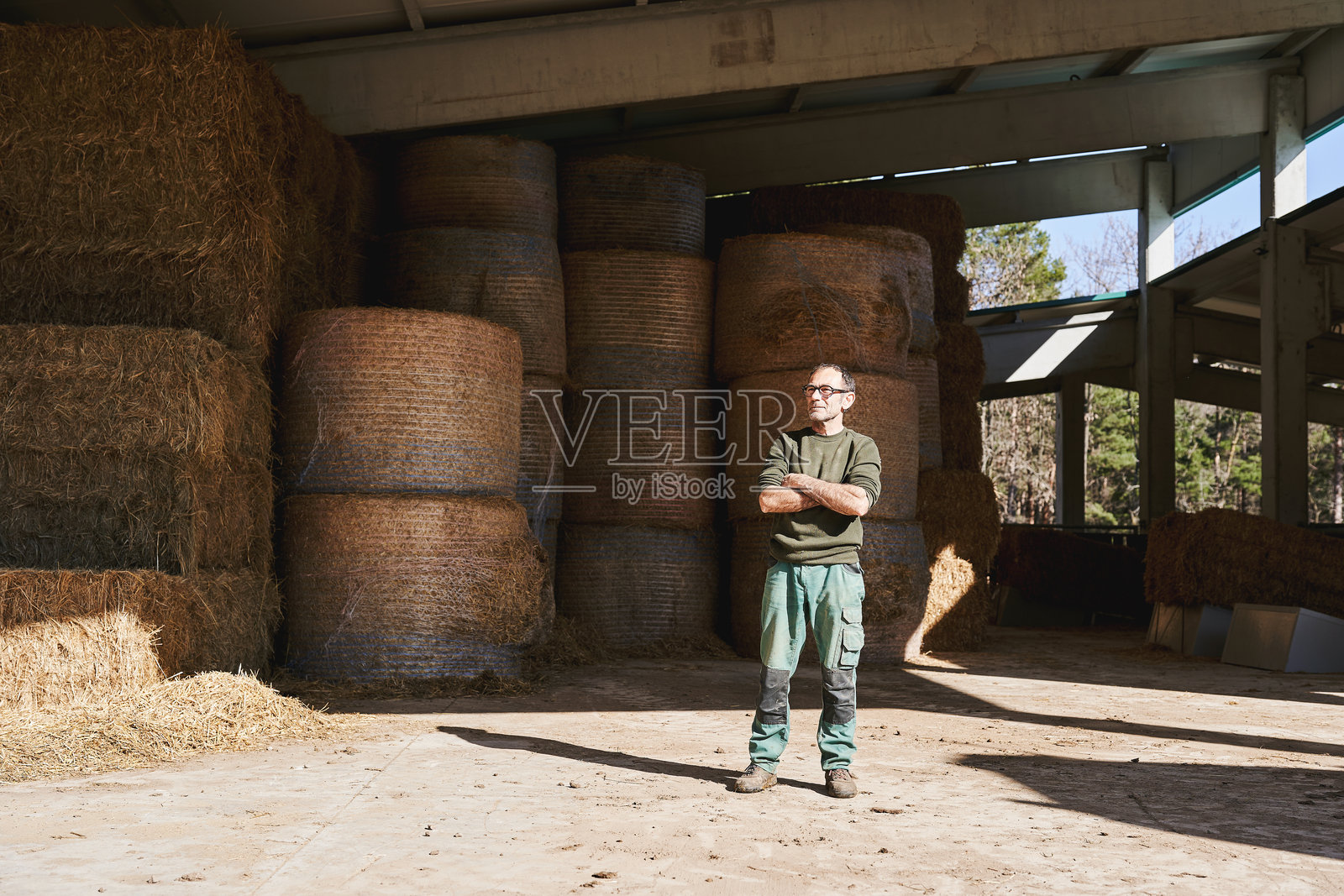 自信的农民站在乡村农场的干草储存棚里照片摄影图片