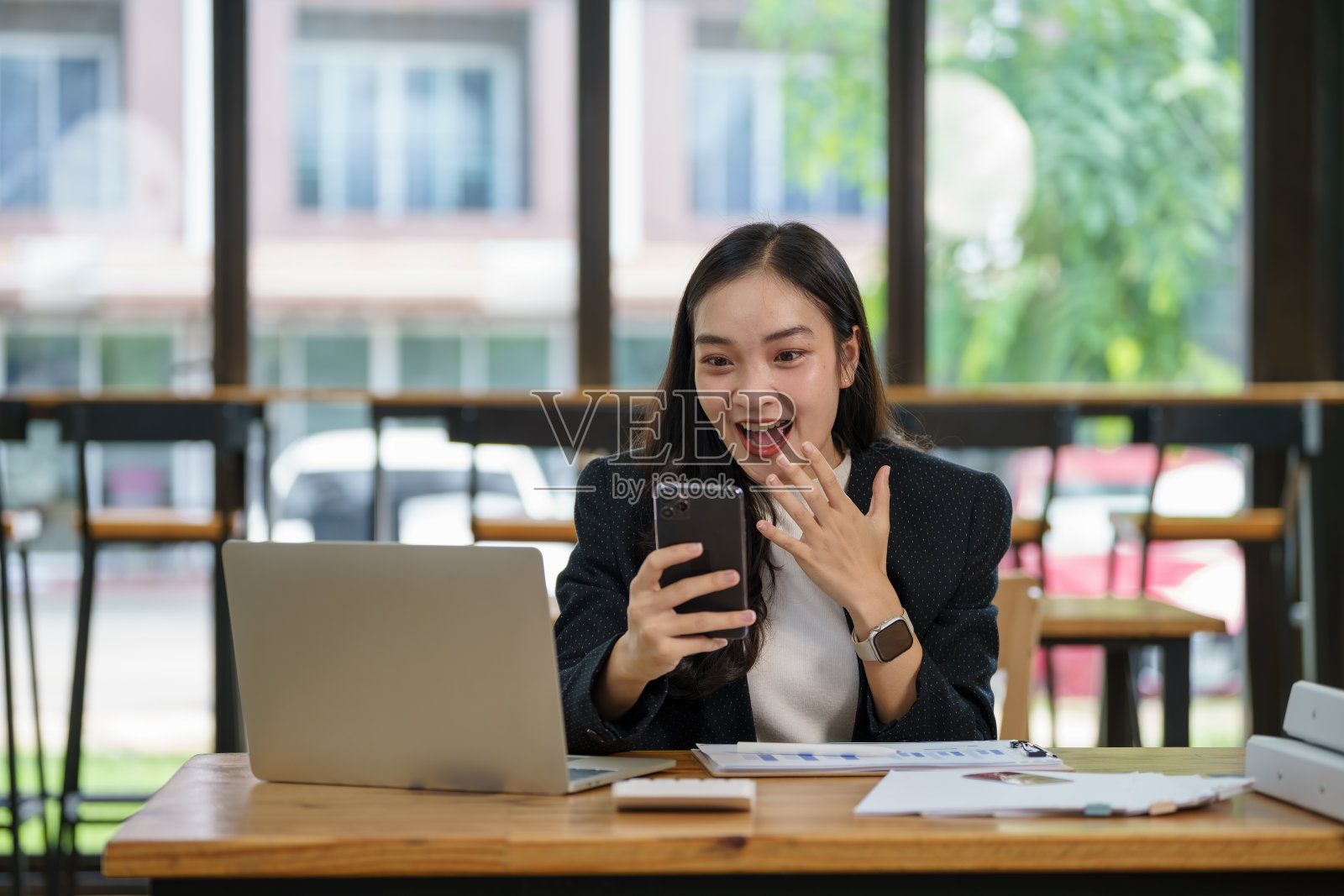 亚洲女商人在办公室用智能手机工作时欢呼。照片摄影图片