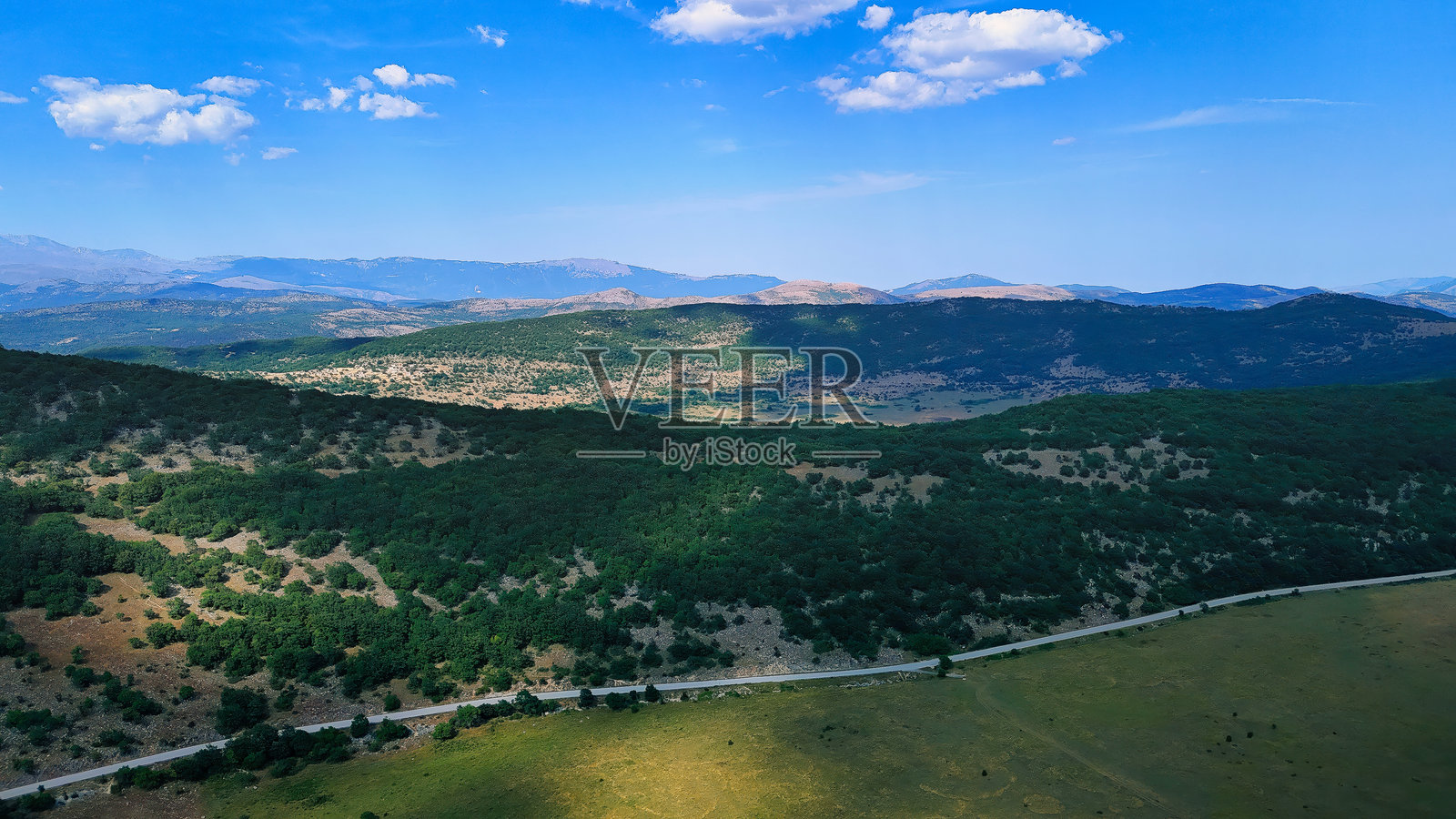 蜿蜒的小路穿过被绿色森林覆盖的山脉照片摄影图片