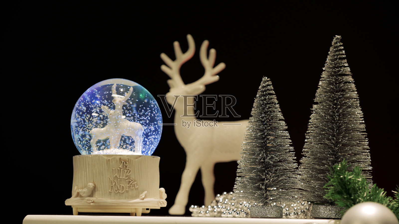 雪花球内有鹿，鹿和松树的雕像，球内的鹿雕像伴随着闪光。照片摄影图片