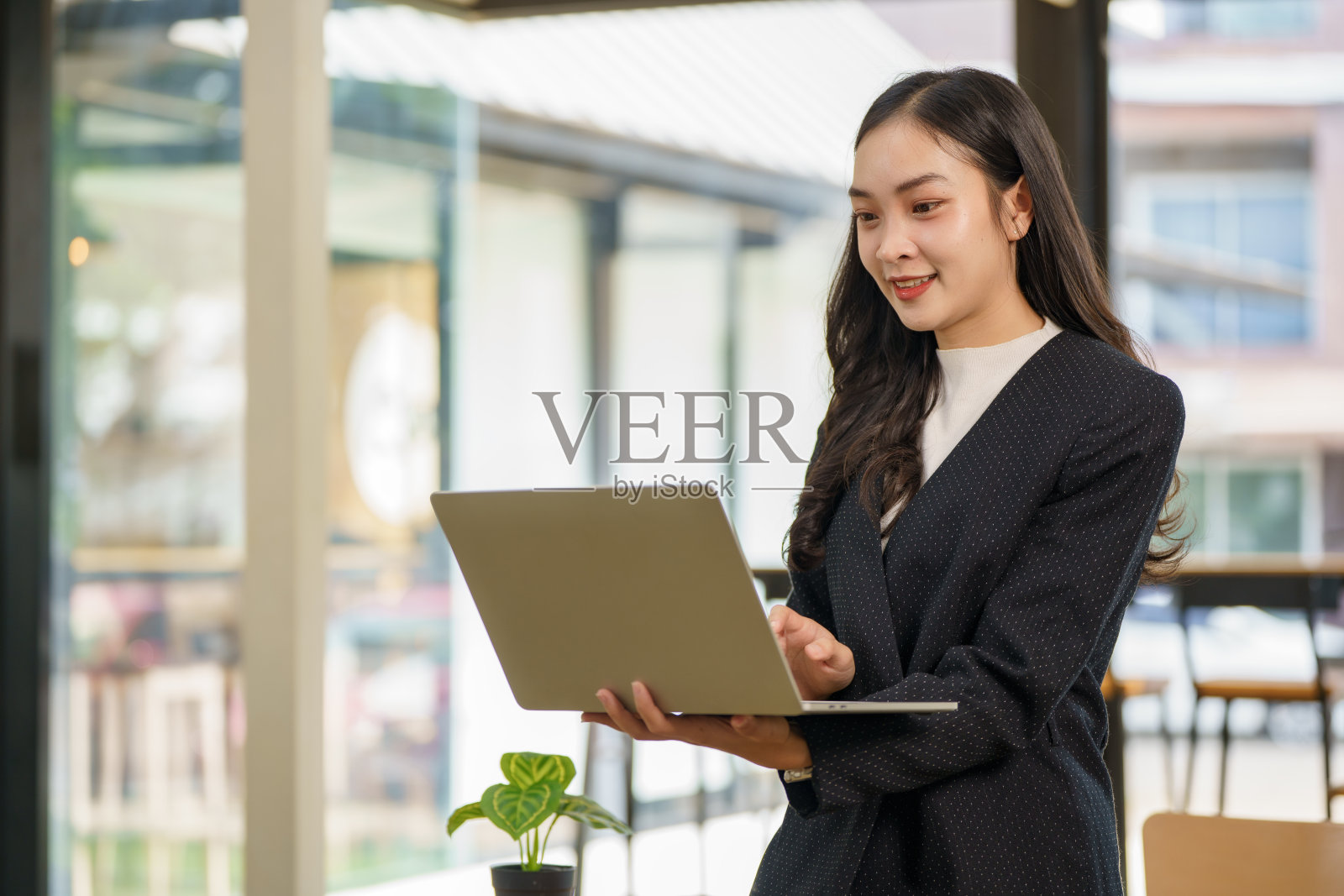 一位年轻的亚洲女商人在现代办公室的桌子旁使用笔记本电脑，正在制定市场营销策略和商业发展计划。照片摄影图片