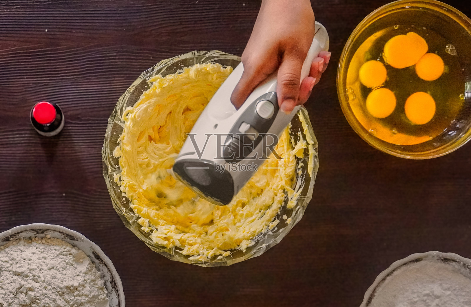 碗中有黄油、生鸡蛋、糖和面粉的蛋糕面糊俯视图 / 在木质背景上用电动搅拌器搅拌照片摄影图片