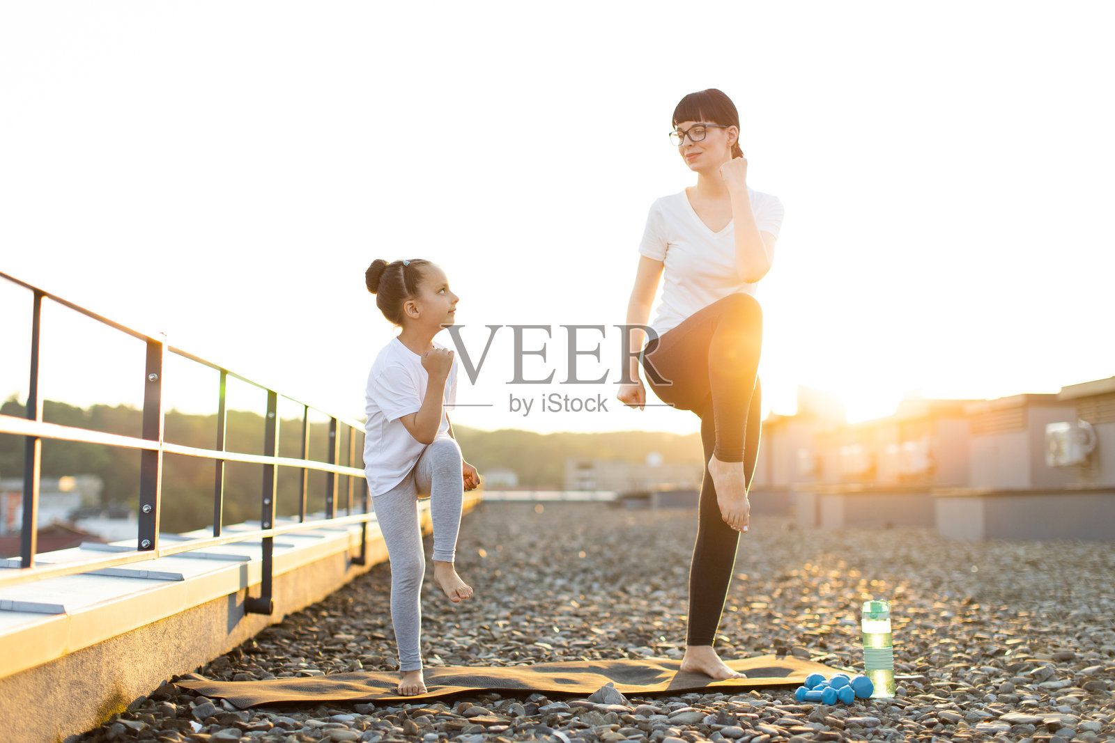 母女在阳光明媚的屋顶上一起进行健身训练照片摄影图片