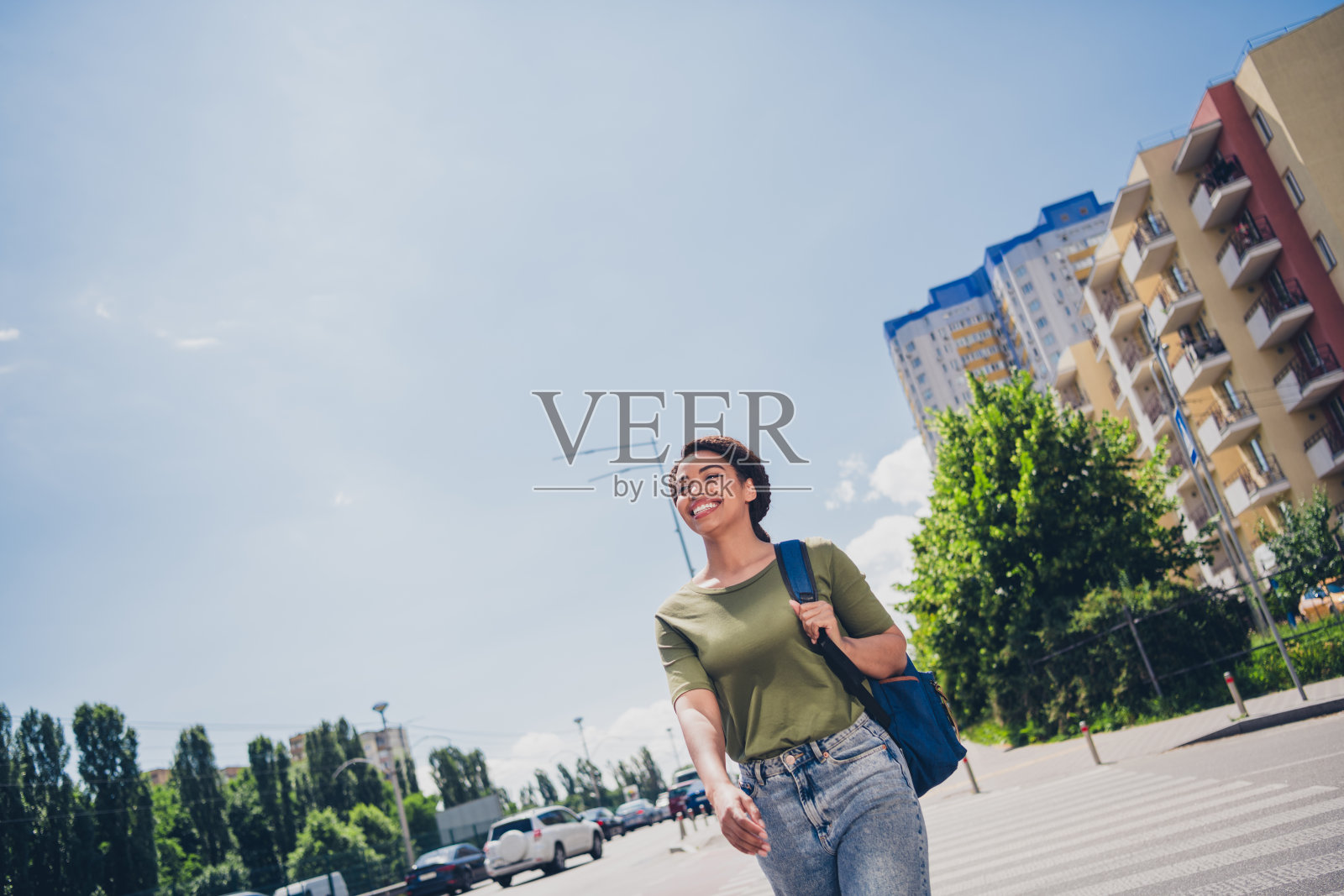 年轻女性在阳光明媚的日子里愉快地走在城市街道上，享受户外休闲时光照片摄影图片