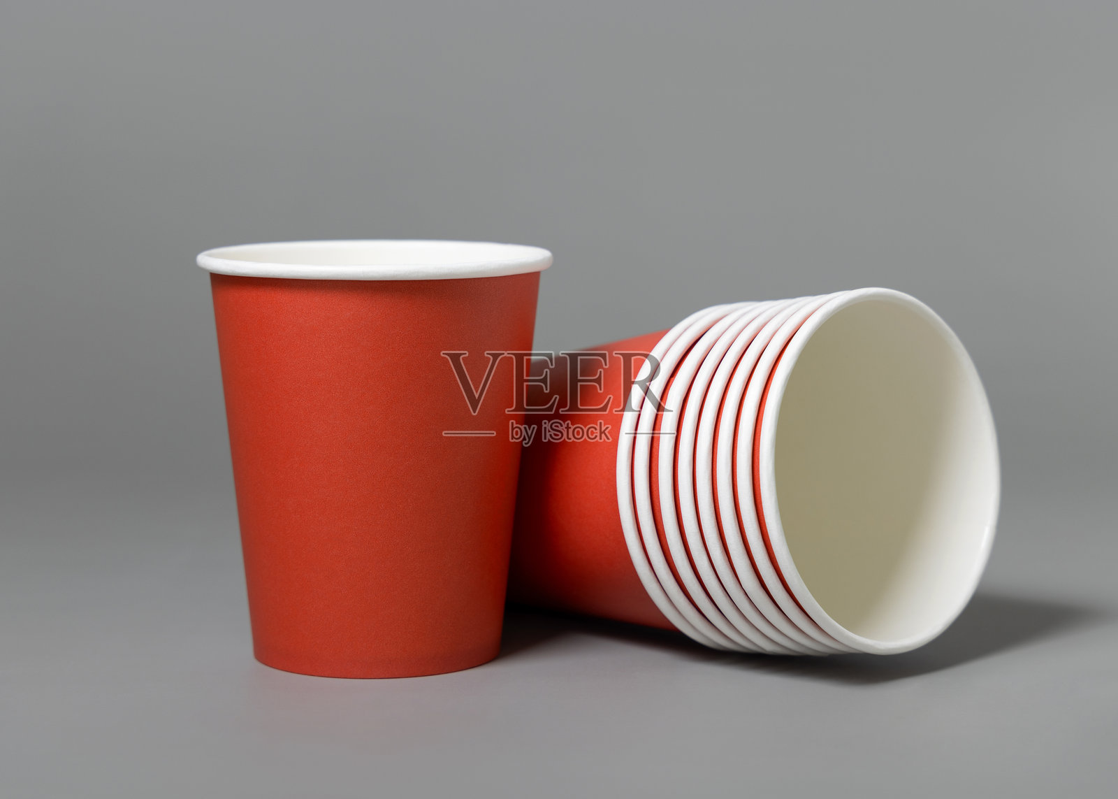 灰色背景上的一次性红色纸杯特写，环保无塑料的圣诞节模版。照片摄影图片
