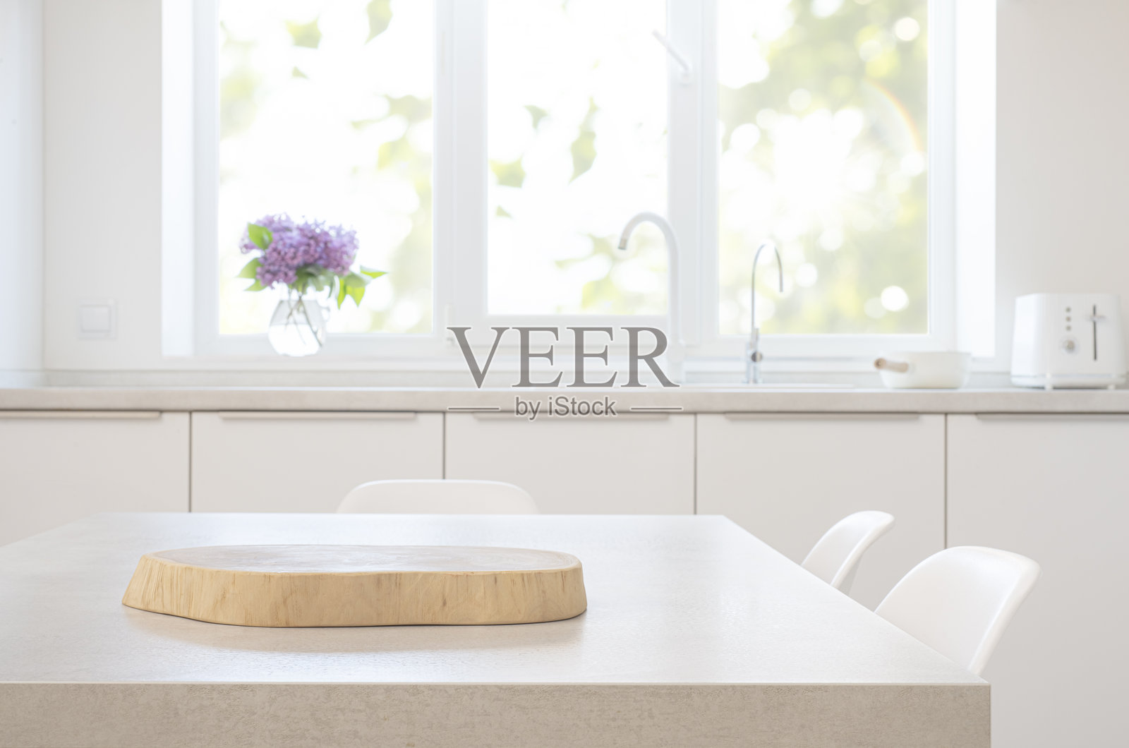 光滑的木质底座放置在灰色桌子上，背景是模糊的日光厨房室内。照片摄影图片