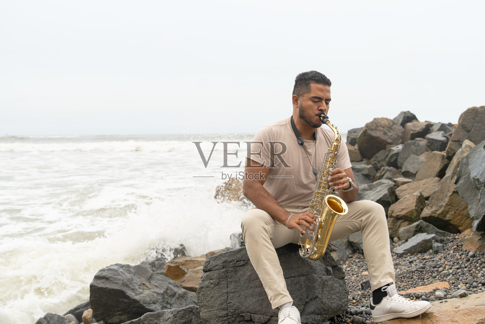 年轻的萨克斯演奏者在海滩上演奏，寻求灵感照片摄影图片