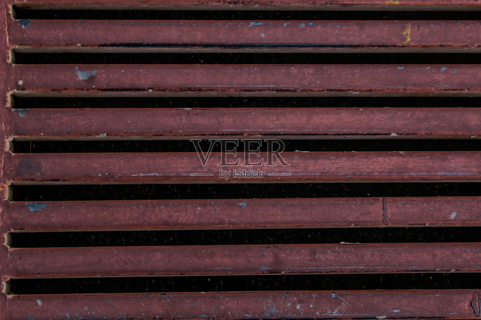 特写镜头展示一块风化的红棕色金属格栅铁网板。水平条纹呈现交替的金属与空隙的图案。照片摄影图片