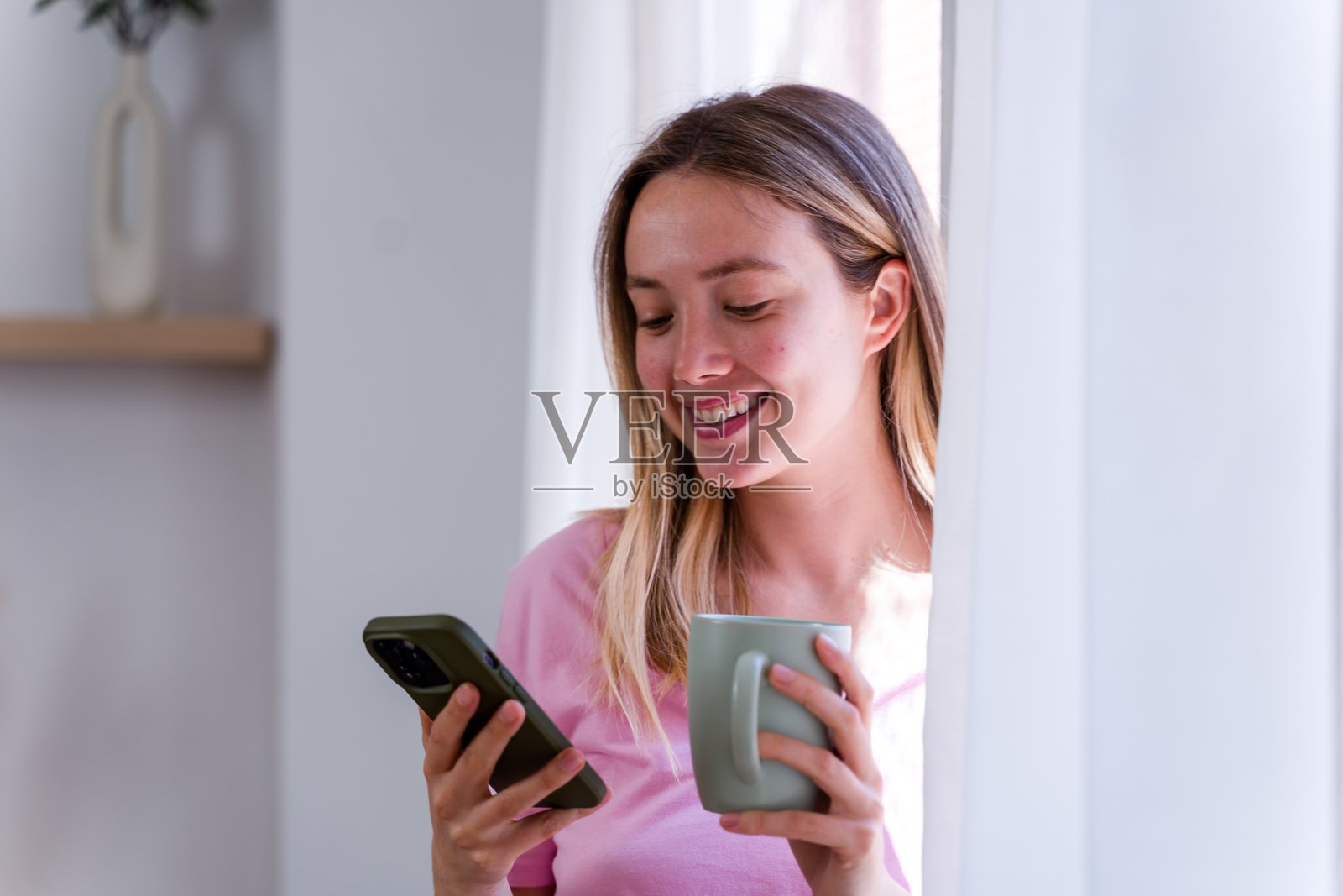 年轻女性一边发短信一边享受早晨咖啡照片摄影图片