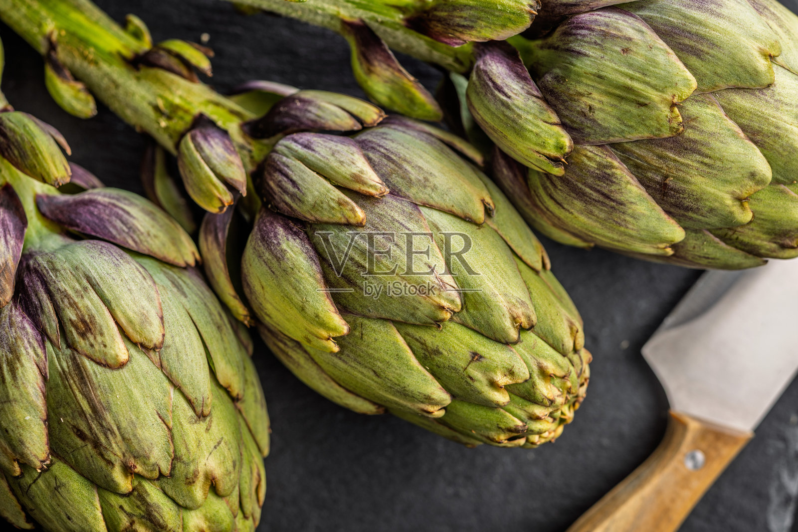 成熟的朝鲜蓟植物在切菜板上。照片摄影图片