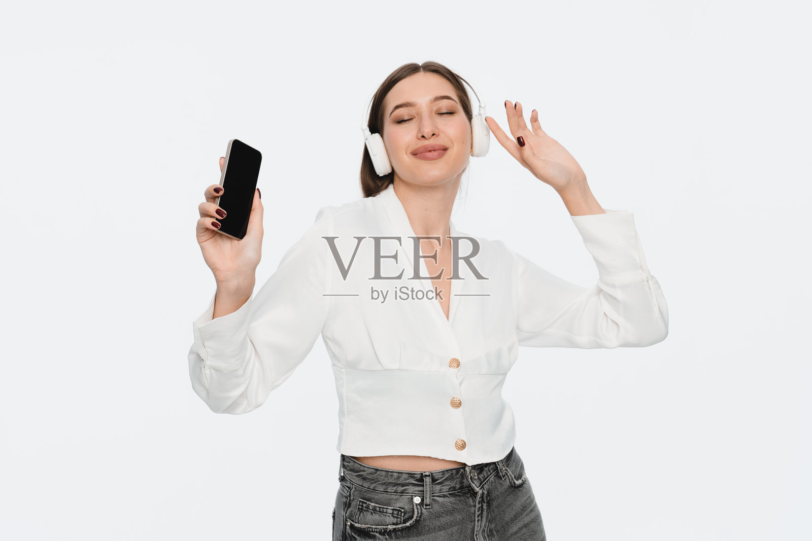 女性佩戴无线耳机听音乐，同时手持智能手机照片摄影图片