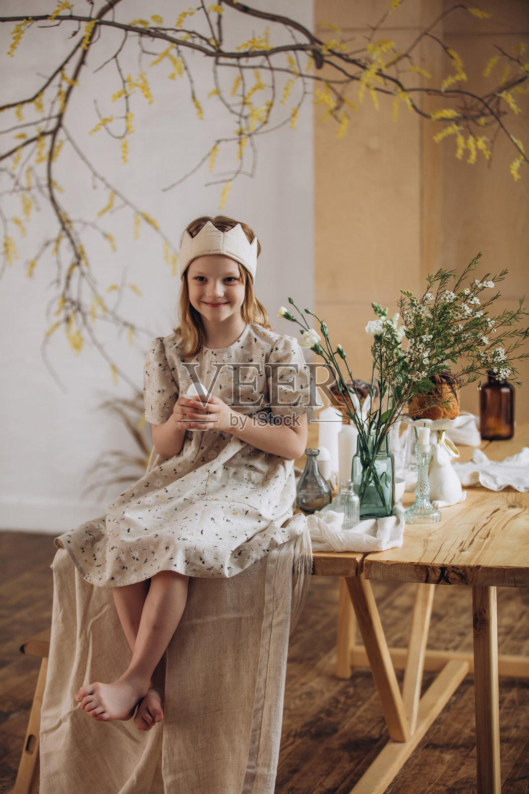 一个学龄前女孩在家中庆祝复活节，坐在桌子旁。照片摄影图片