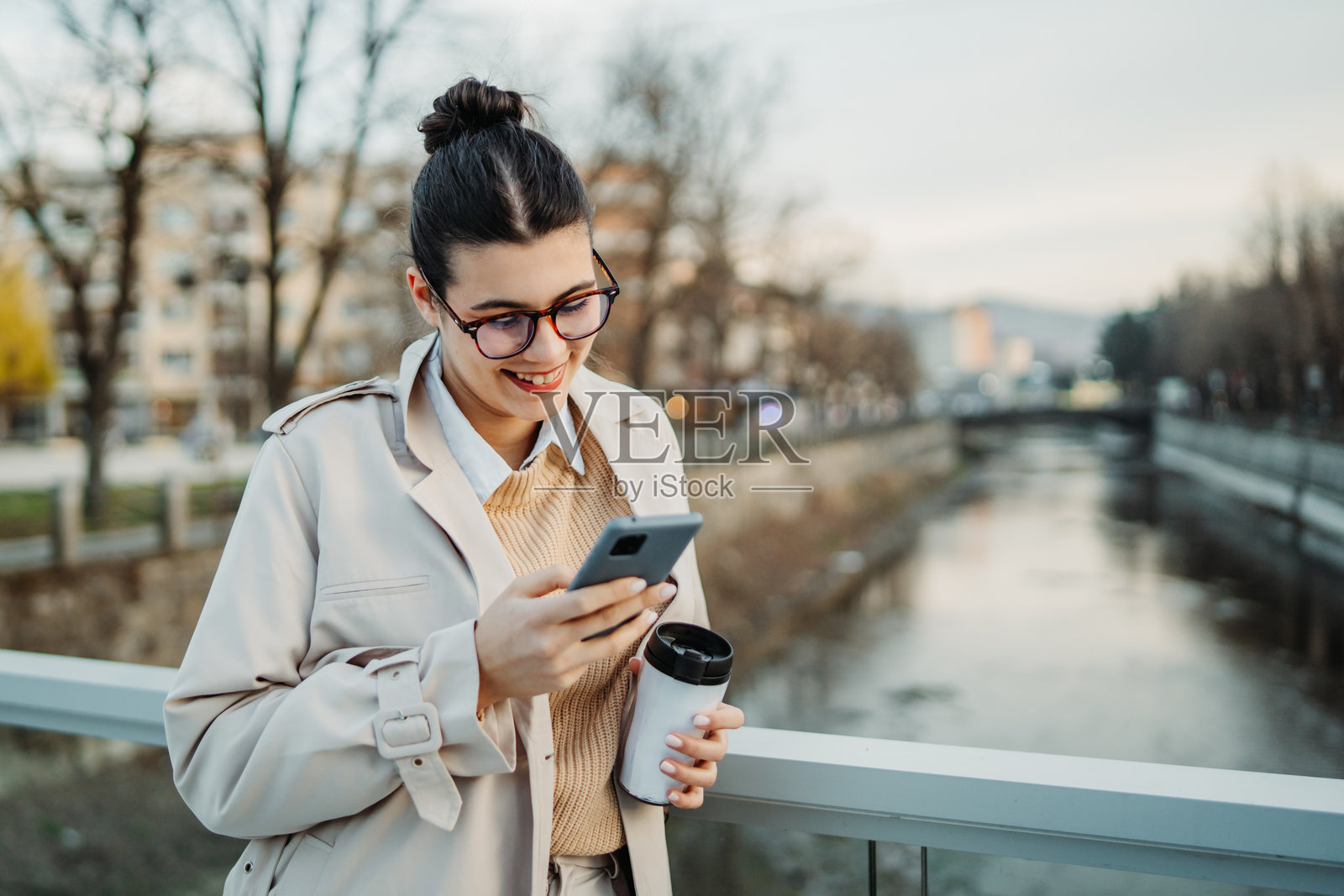年轻的白人女性下班回家，喝着咖啡并使用手机。照片摄影图片