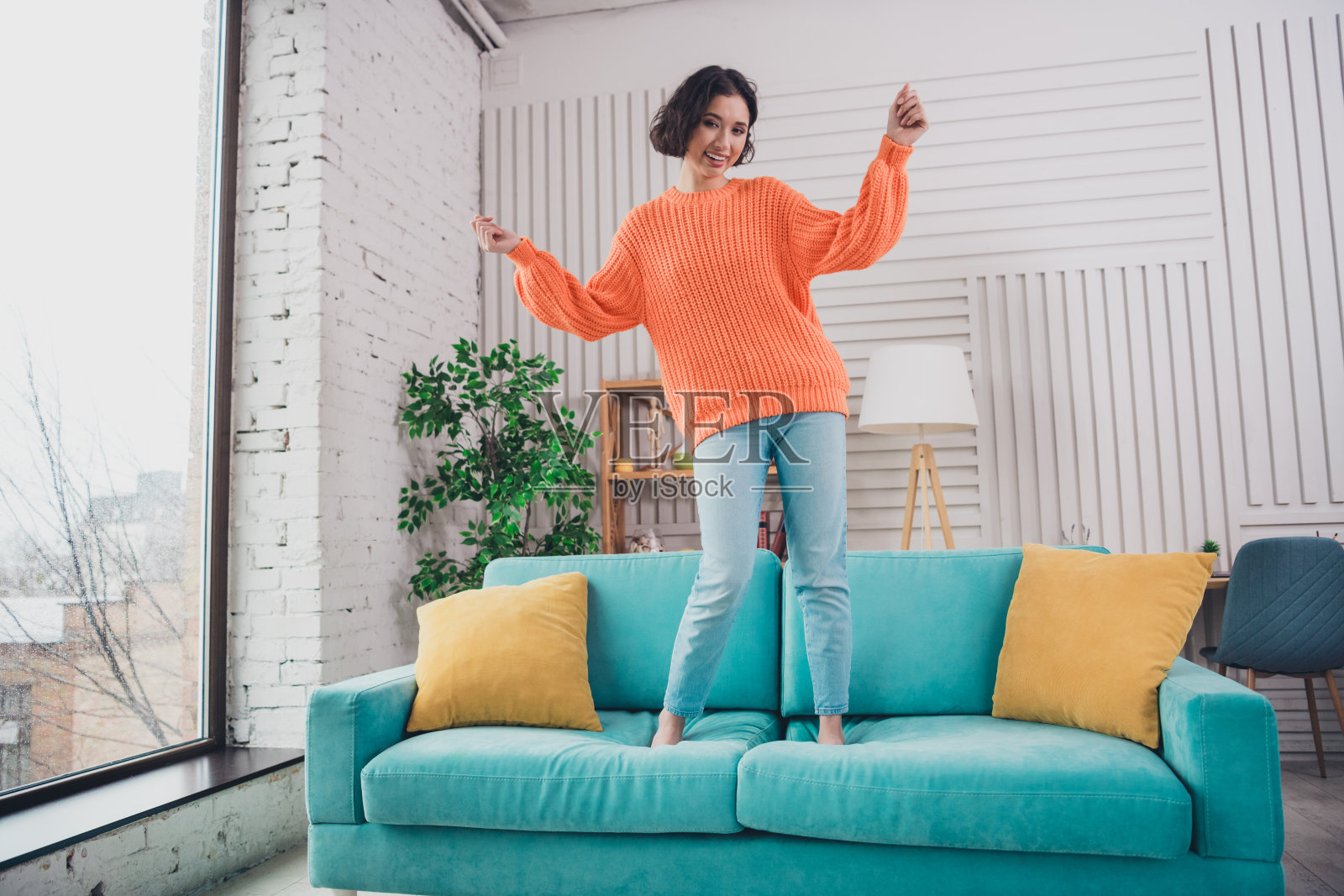 年轻快乐的女性坐在现代舒适的客厅里，享受着在充满活力的沙发上度过的悠闲时光。照片摄影图片