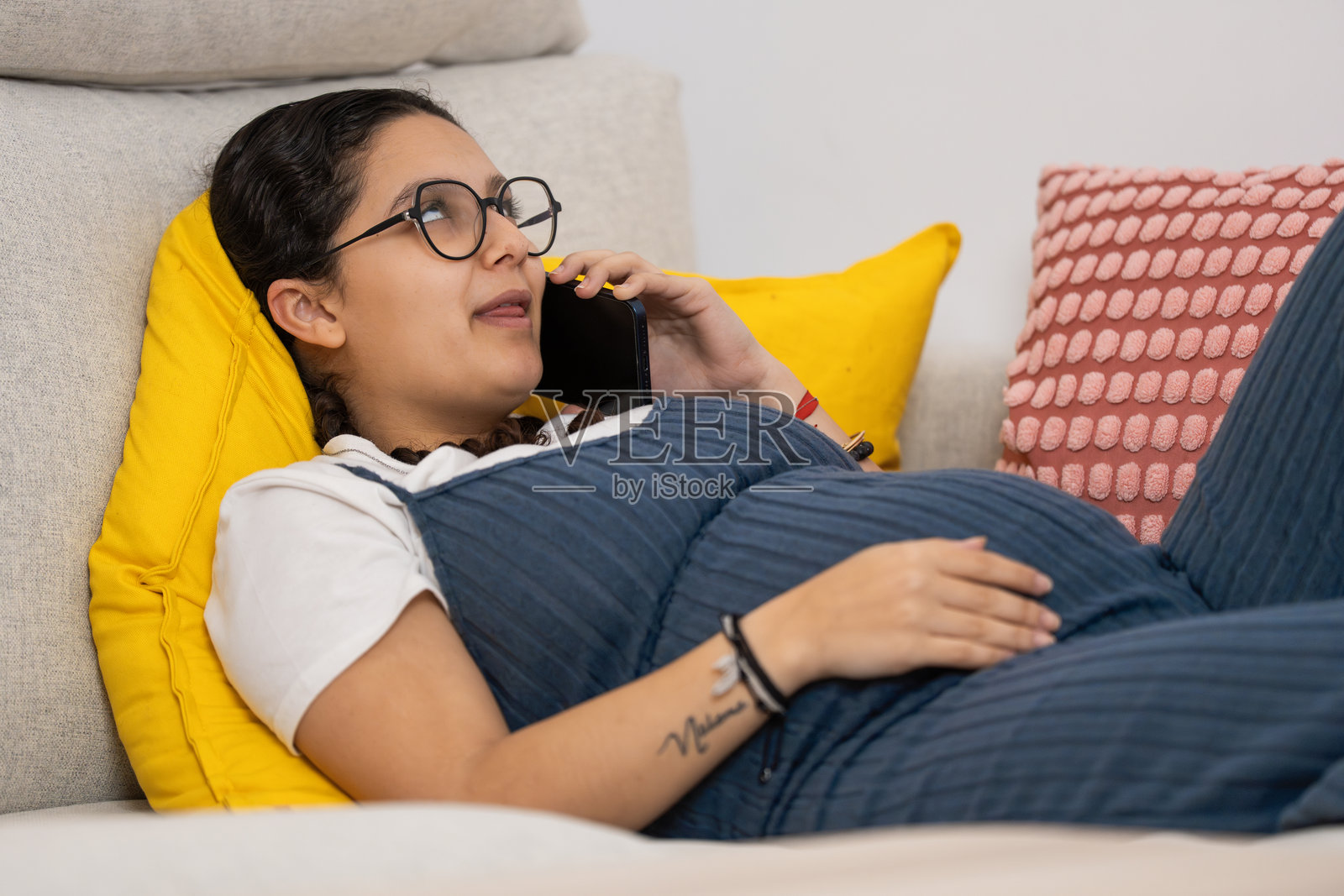 沙发上的孕妇正在用智能手机通话照片摄影图片