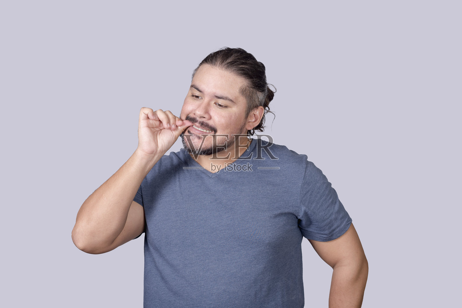 一位三十多岁的胡子男人出于习惯咬指甲。一个感到紧张的神经质家伙。强迫行为被称为甲咬癖。照片摄影图片