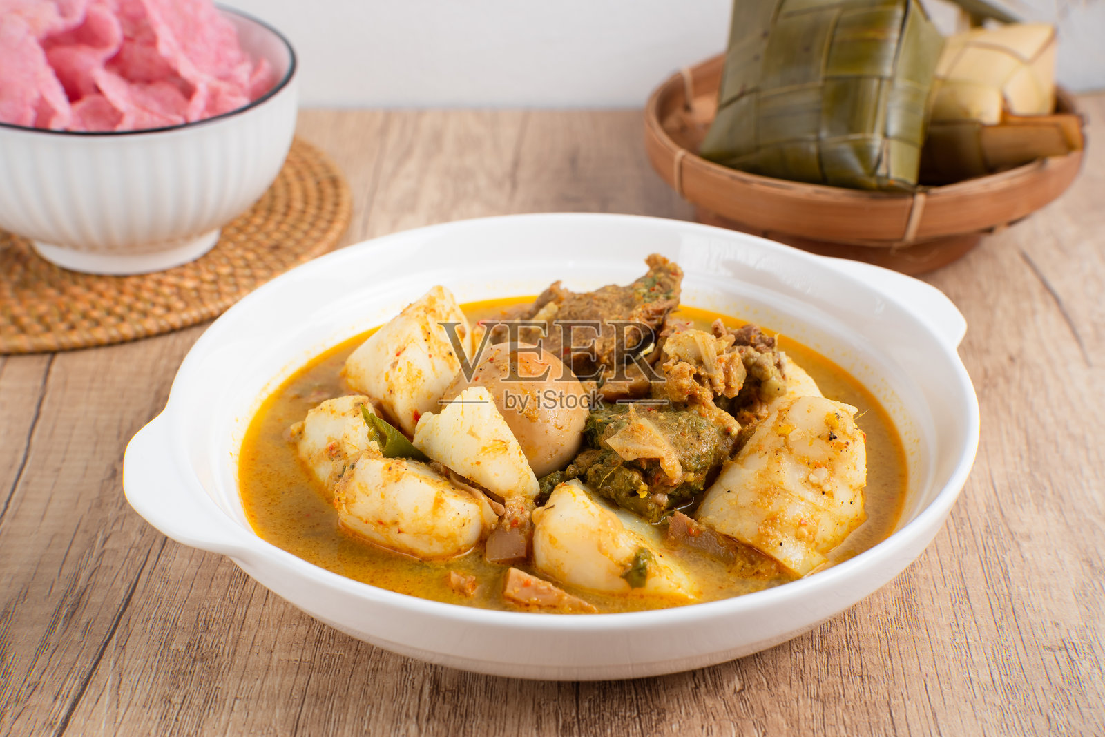 巴东椰浆饭是印尼西苏门答腊米南族的招牌菜之一，通常盛在白色盘子里，配有椰子咖喱酱、菠萝蜜蔬菜、煮鸡蛋和仁当。照片摄影图片