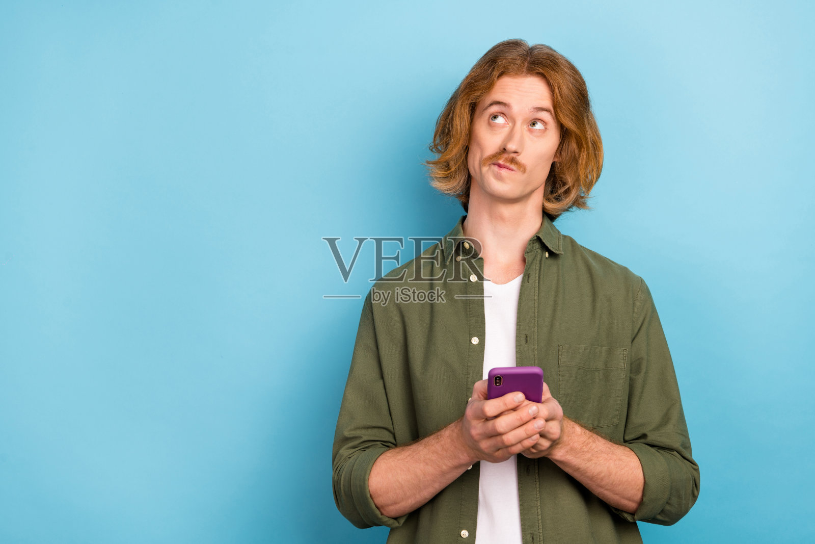 一位迷人的时尚男士在明亮的蓝色背景下使用设备应用程序5G创建新帖子，留有空白空间。照片摄影图片