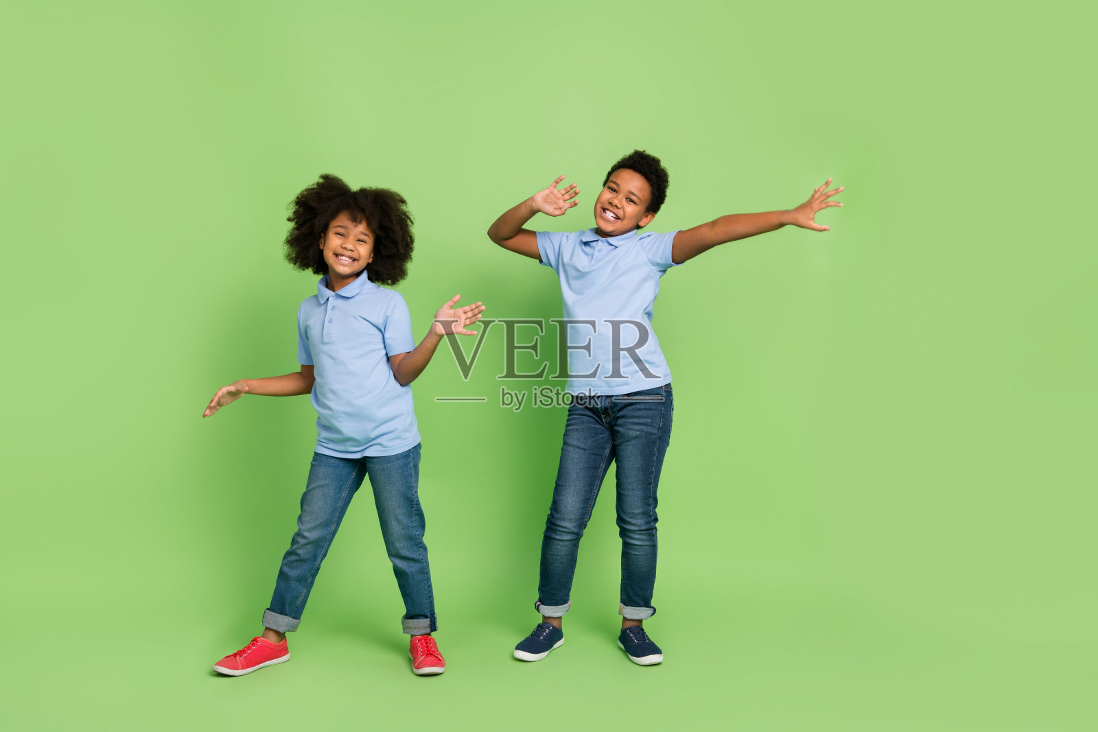 吸引人的快乐时尚少年在绿色背景下跳舞，展现全身形象。照片摄影图片