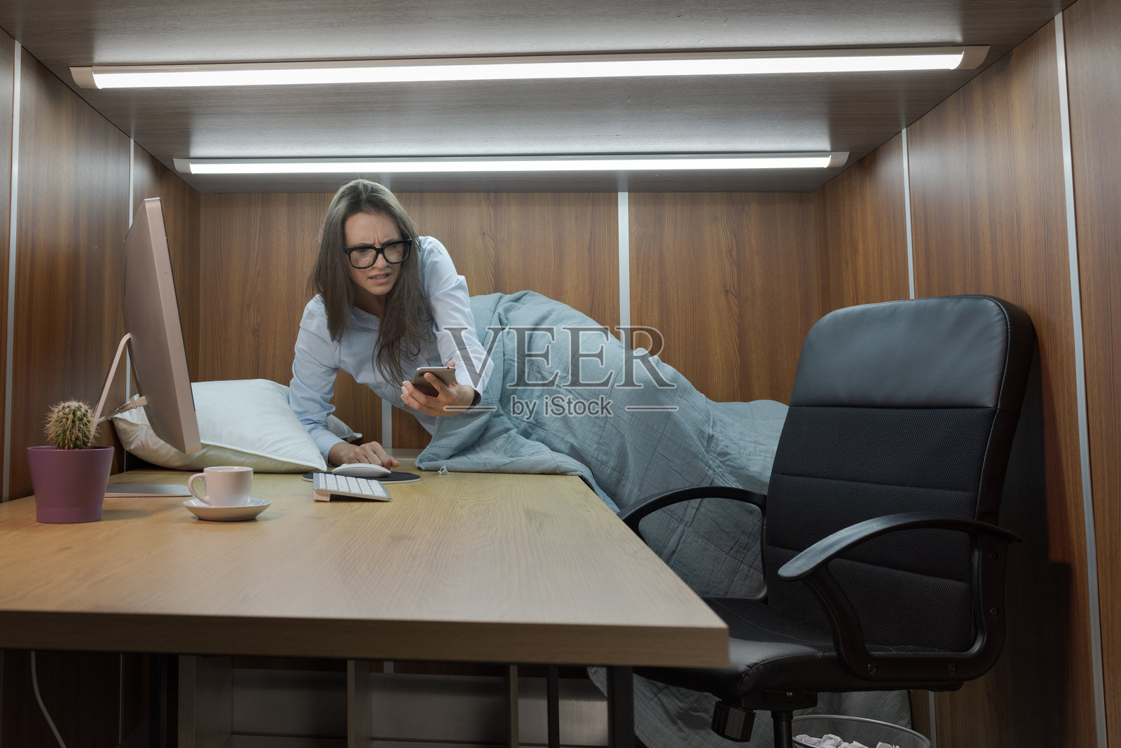 感到压力和沮丧的女性在小办公室里一边工作一边睡觉照片摄影图片