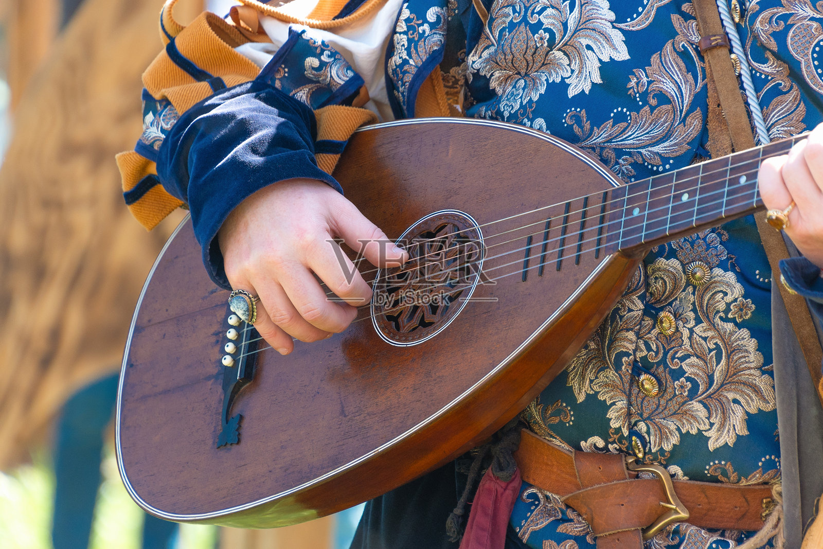 Renaissance festival musician playing a lute in ornate costume照片摄影图片
