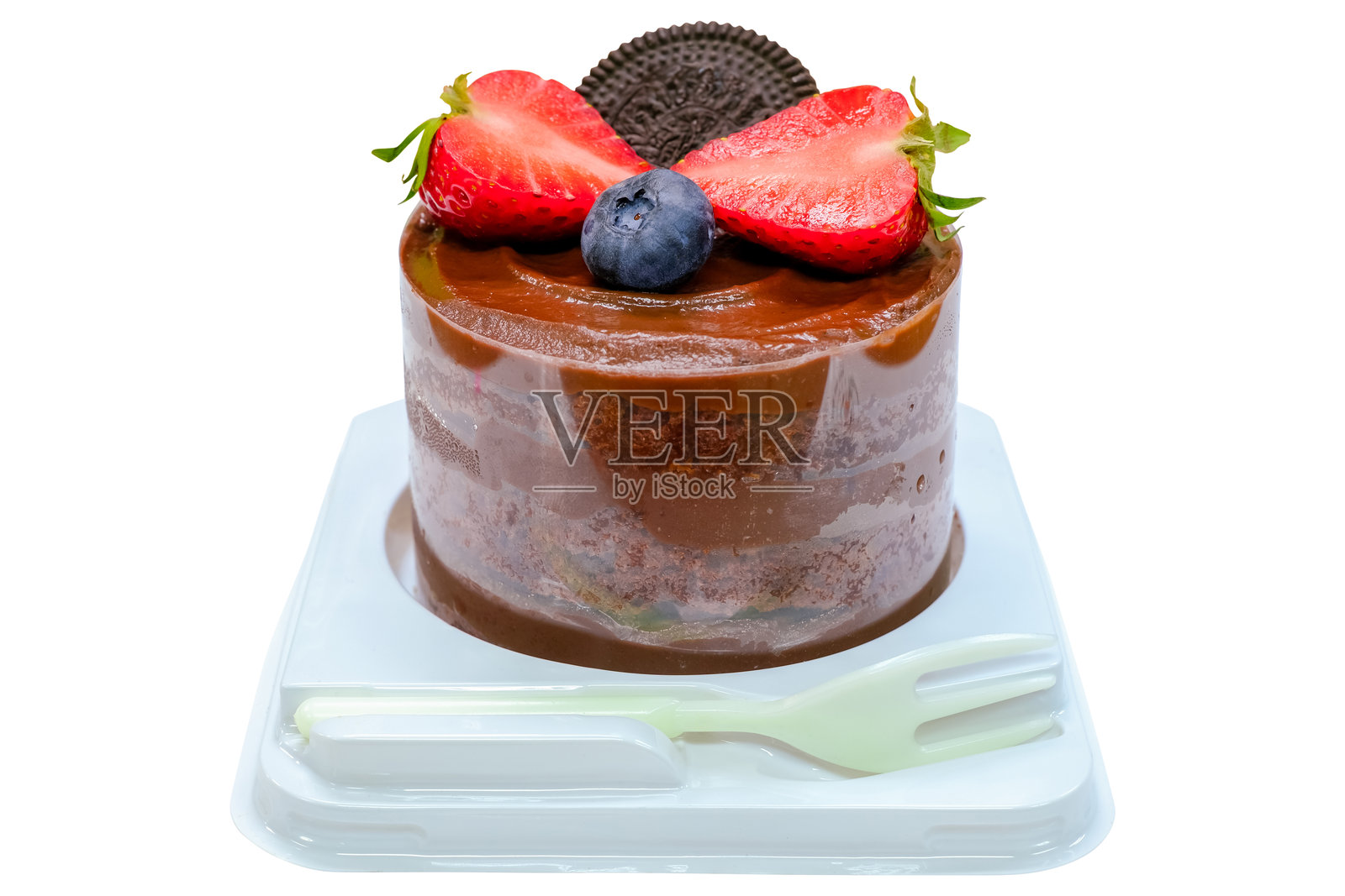 美味的甜巧克力蛋糕，上面装饰着新鲜草莓、一颗蓝莓和一块饼干，放在塑料容器中，配有塑料叉。背景为白色，带有抠图路径。照片摄影图片