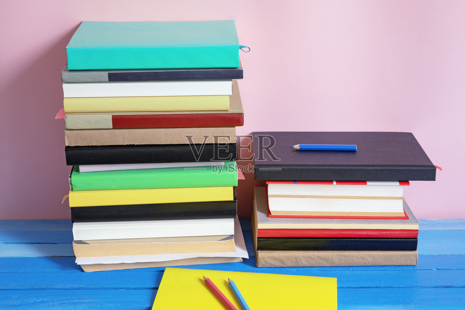 两堆色彩斑斓的书籍放在蓝色的复古桌子上。留白空间。照片摄影图片