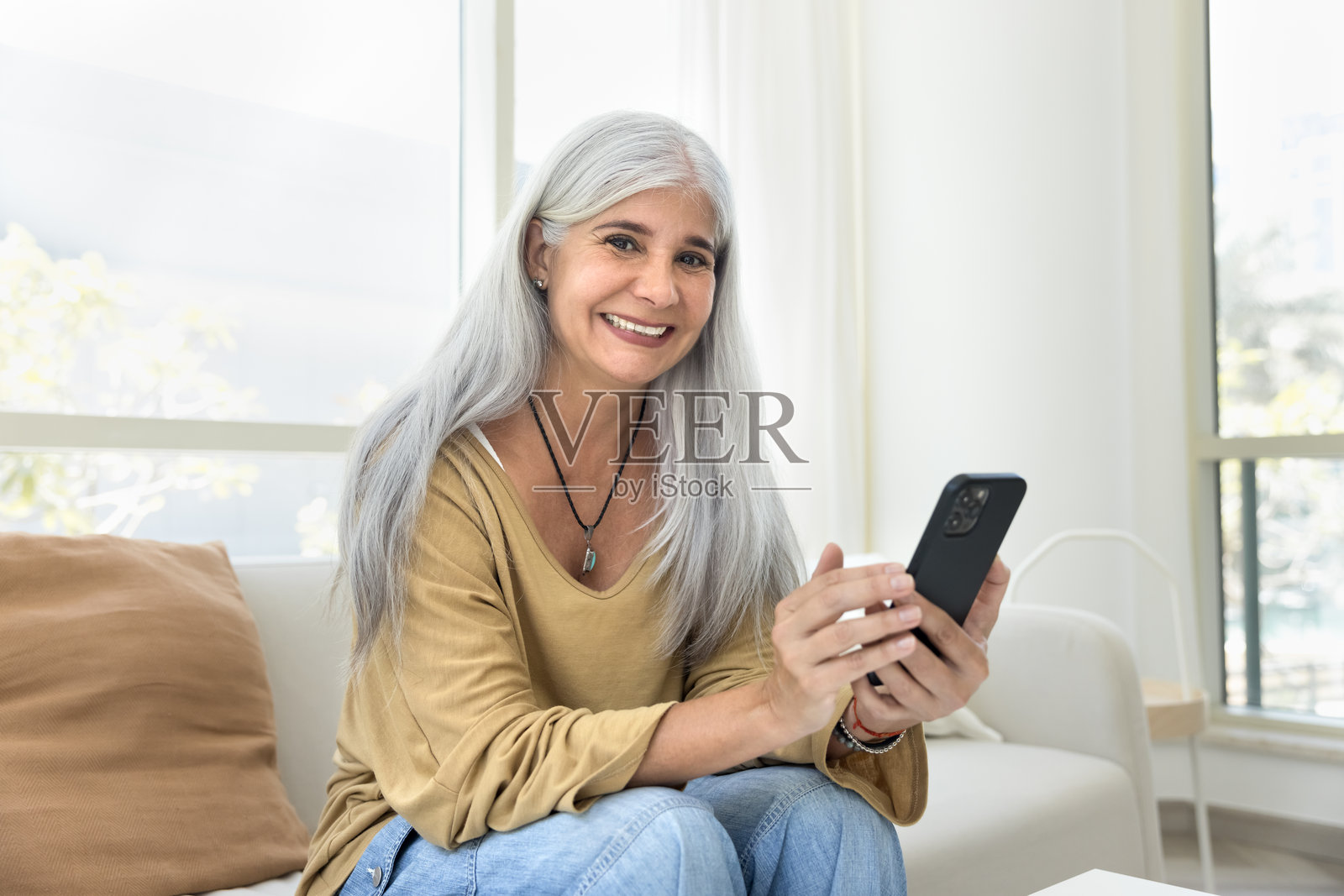 快乐的灰发拉丁裔老年女性使用在线应用程序照片摄影图片