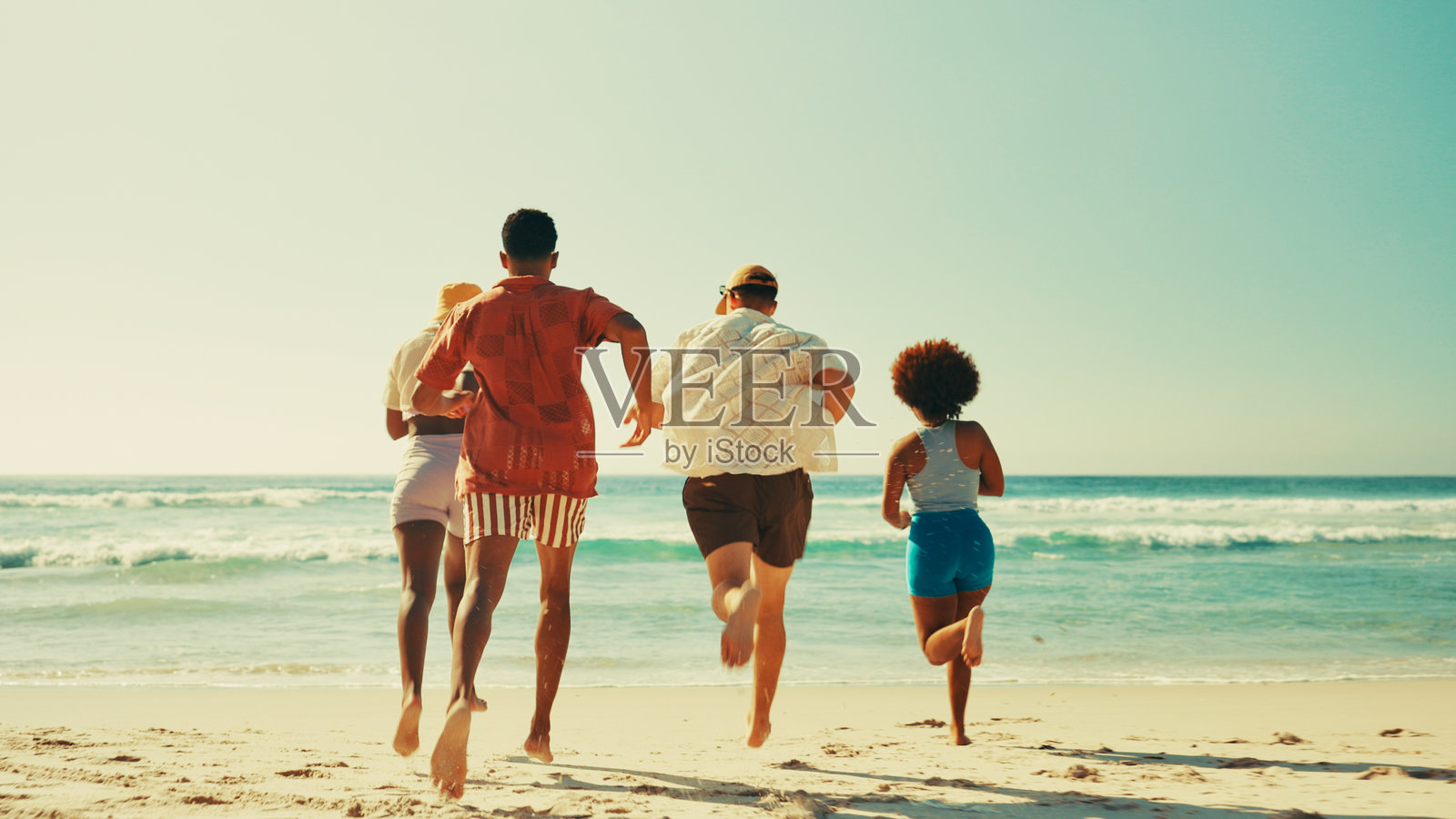 朋友们在海滩上奔跑，享受夏季的假期和社交，海浪拍打着岸边，户外探险。人们在岛上团聚，享受大自然的乐趣，在阳光下愉快地度过海洋假期。照片摄影图片