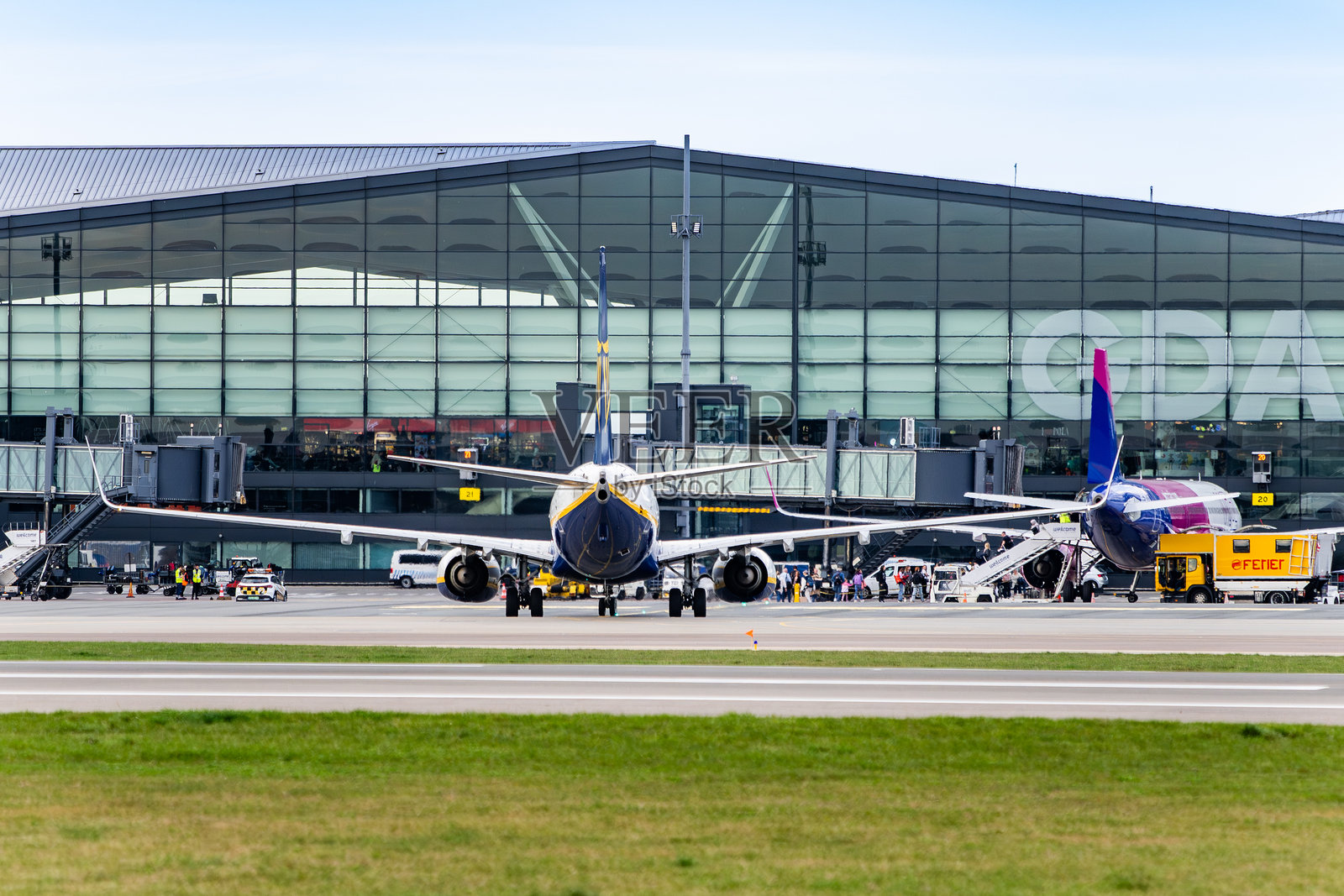 在格但斯克莱赫·瓦文萨机场航站楼，瑞安航空飞机停靠在登机桥旁，与维兹航空飞机并排。照片摄影图片