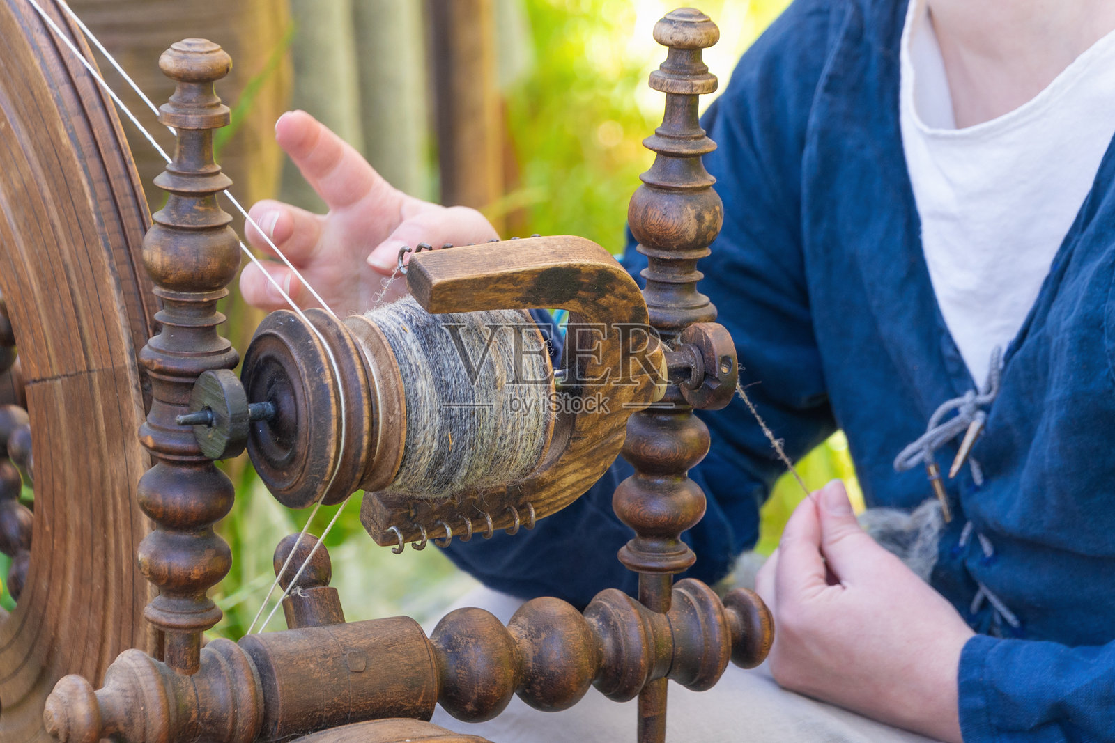 白人女性在户外使用木轮进行传统纺纱照片摄影图片