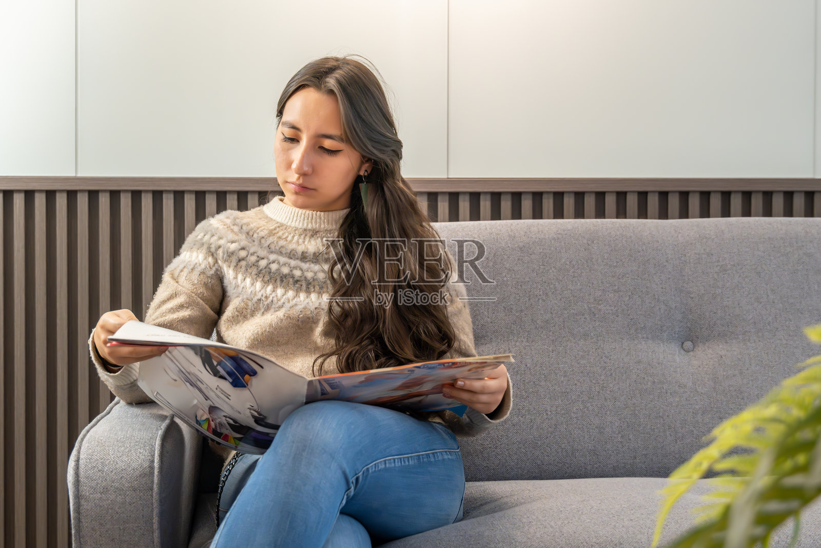 候诊室中的年轻女性与杂志照片摄影图片