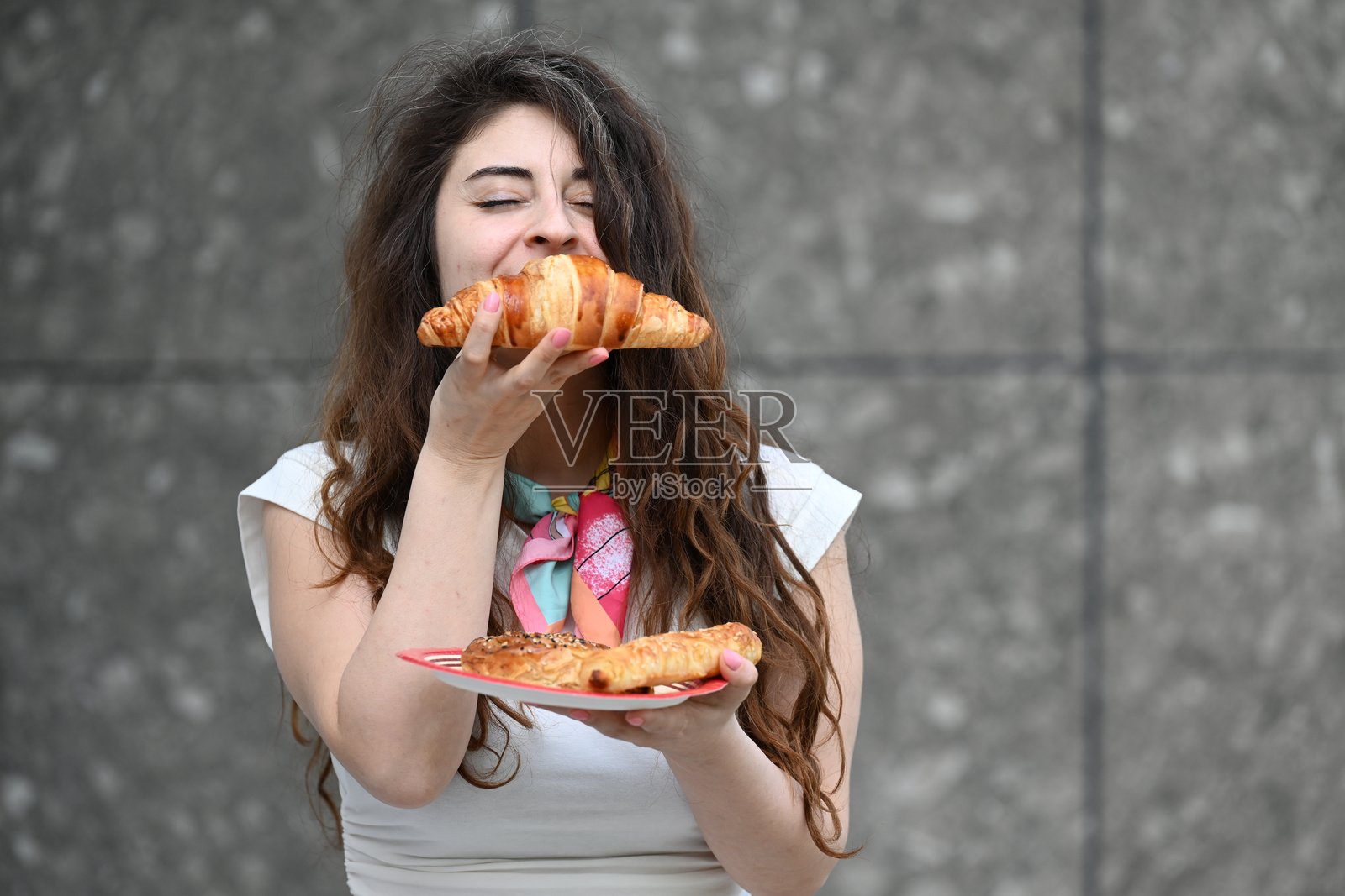 微笑着的迷人女性正在享用可颂面包照片摄影图片