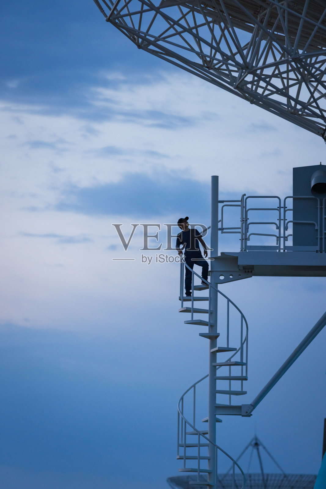 一名工程师在日落时修理卫星接收器。照片摄影图片