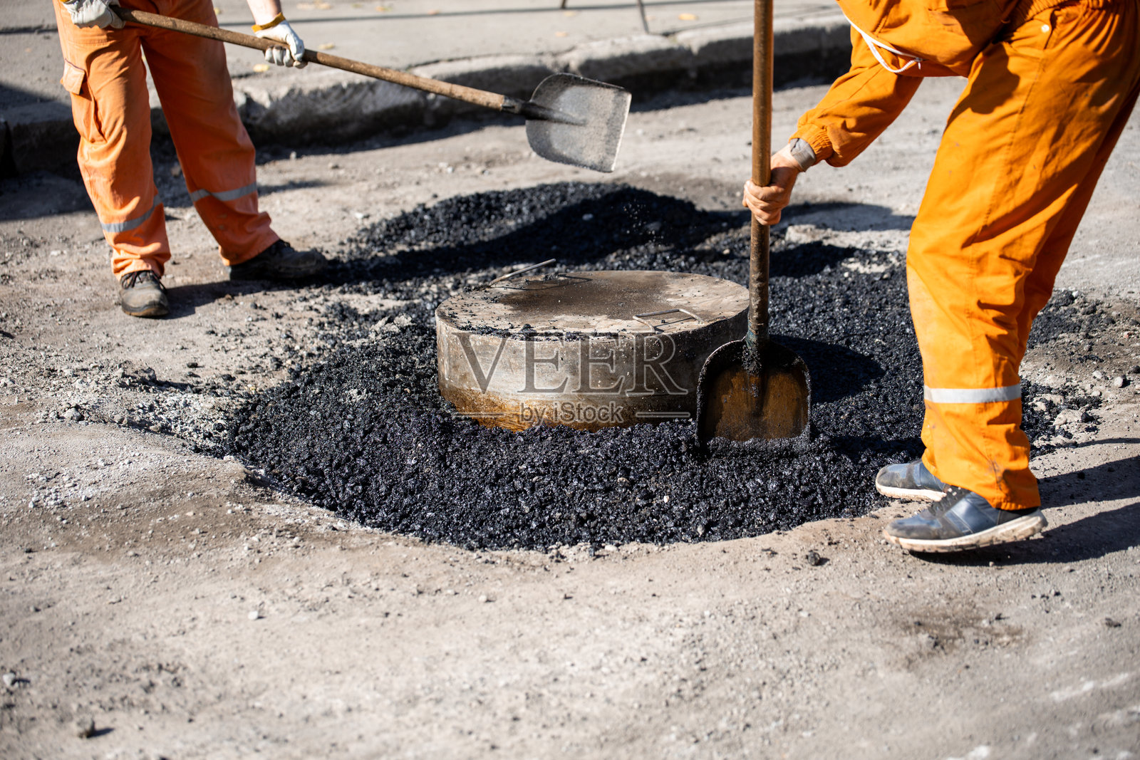 工人在城市街道上穿着安全装备修补沥青路面照片摄影图片