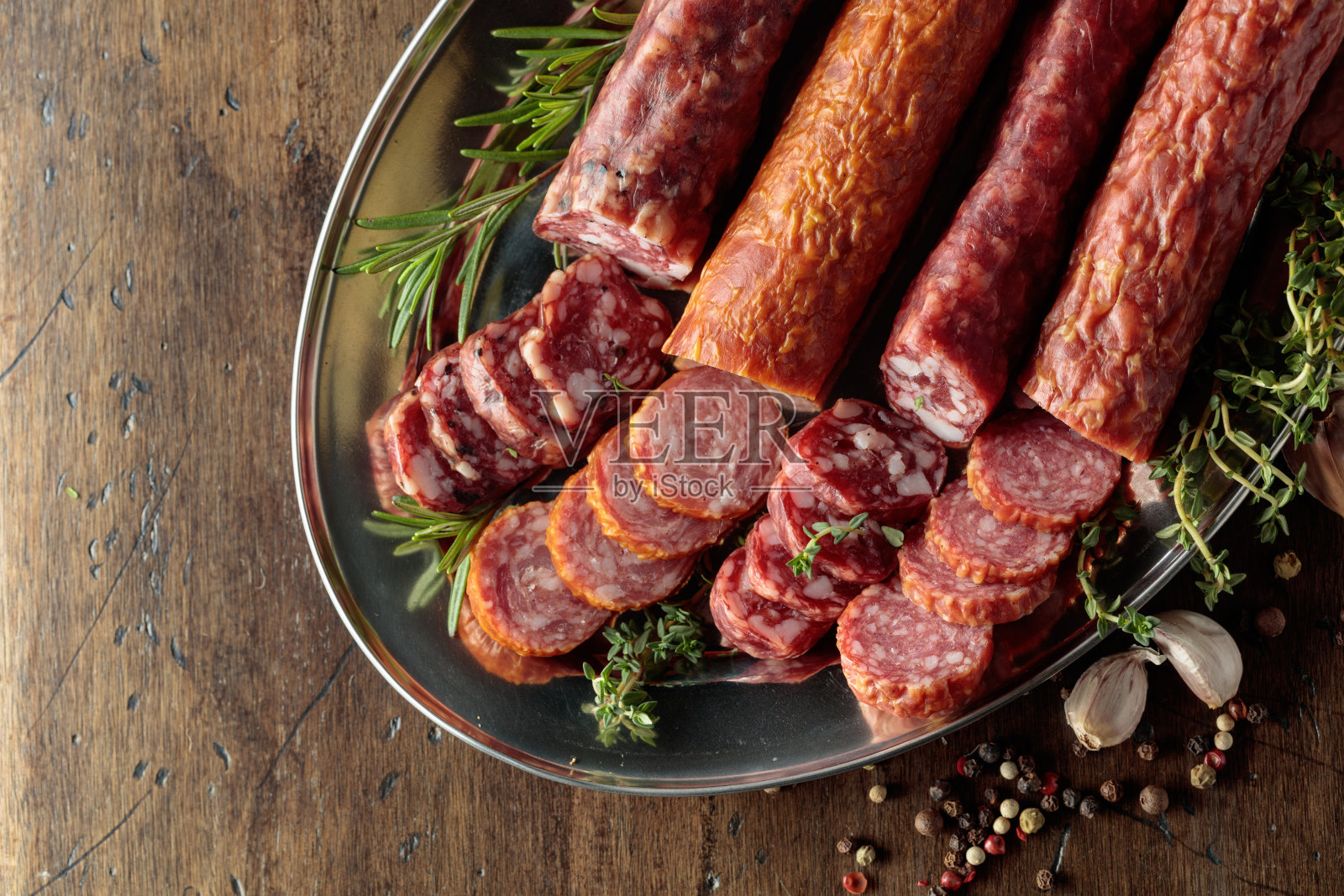 切片的干腌香肠，配有胡椒粒、百里香、迷迭香和大蒜。照片摄影图片