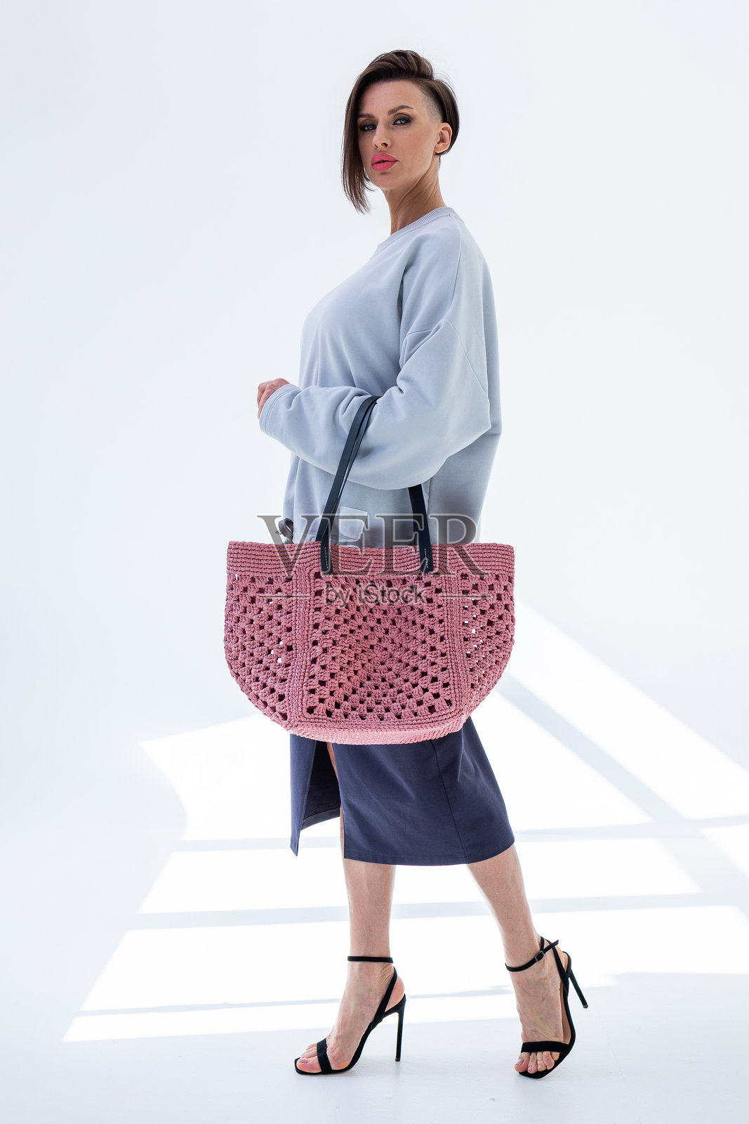 女性手持时尚的粉色编织包。时尚与奢华配饰。底部视角。竖版照片。照片摄影图片