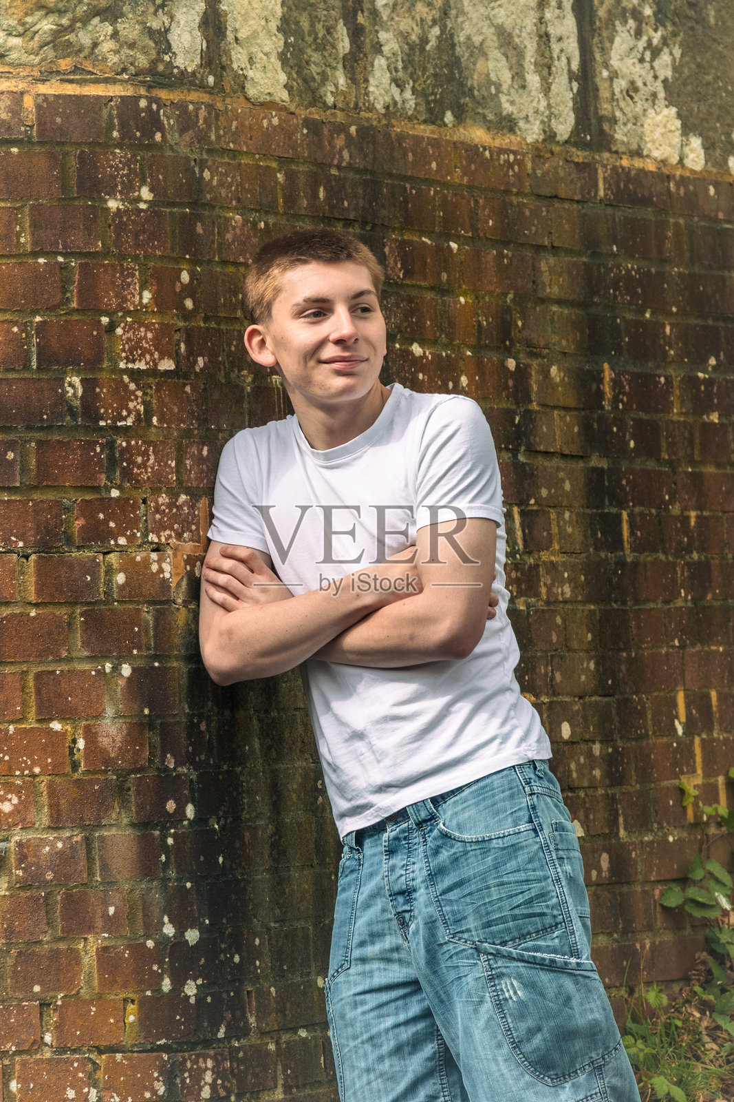 一个靠在砖墙上的少年男孩照片摄影图片