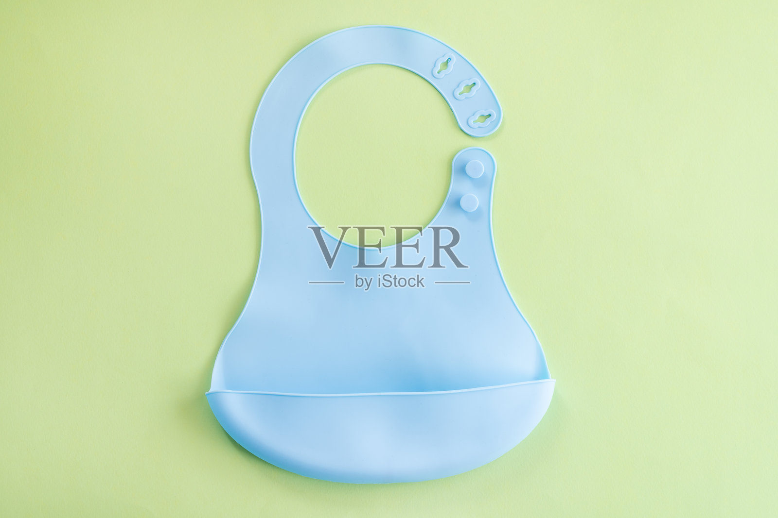 浅绿色背景上的蓝色硅胶婴儿围嘴照片摄影图片