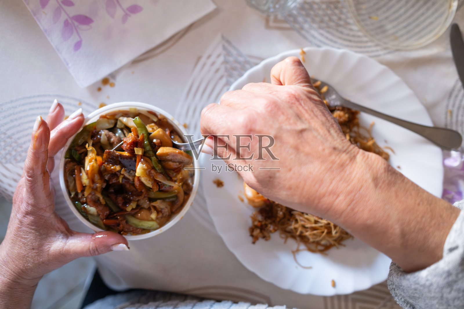 一位年长女性在家中享受美味的中式外卖餐。照片摄影图片
