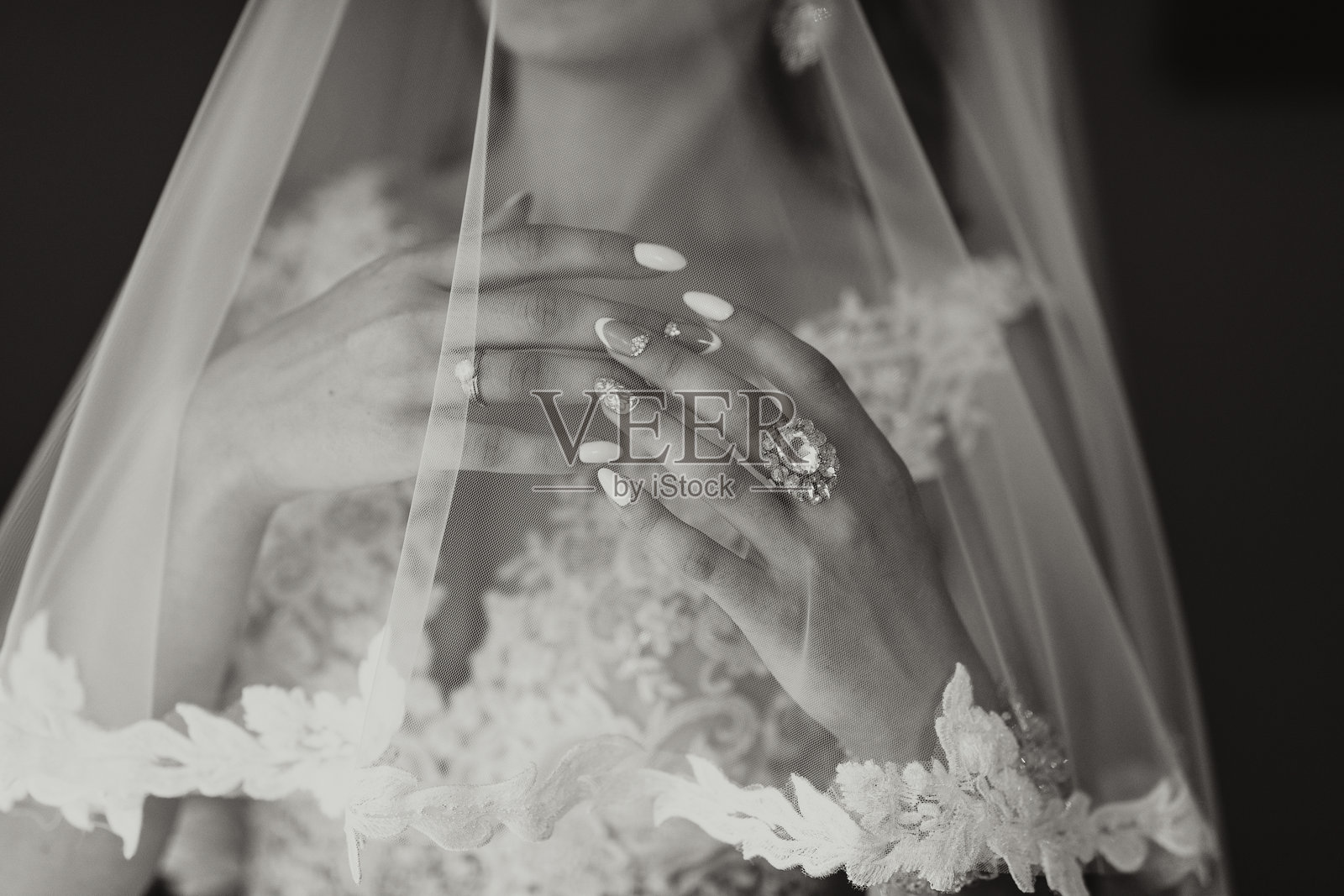 一位女性戴着蕾丝面纱，手指上戴着戒指。照片摄影图片