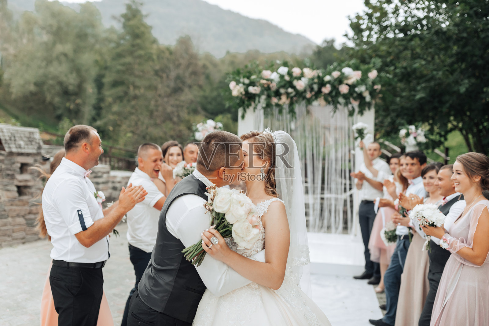 一对新人在一群人面前亲吻照片摄影图片